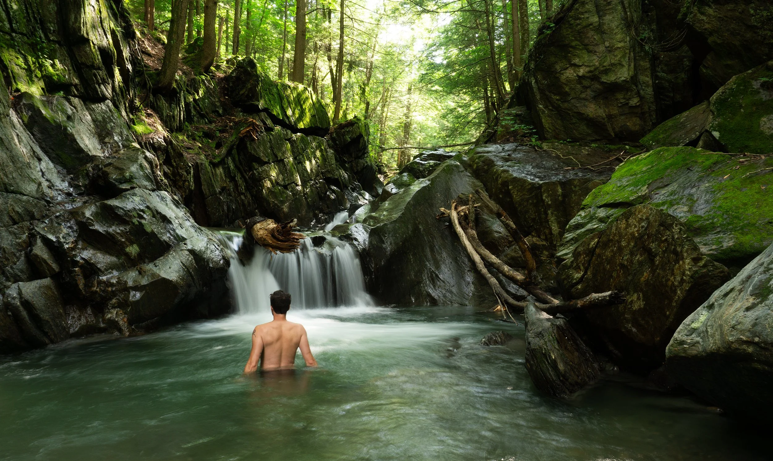 man in an emerald green swimming hole in northern vermont