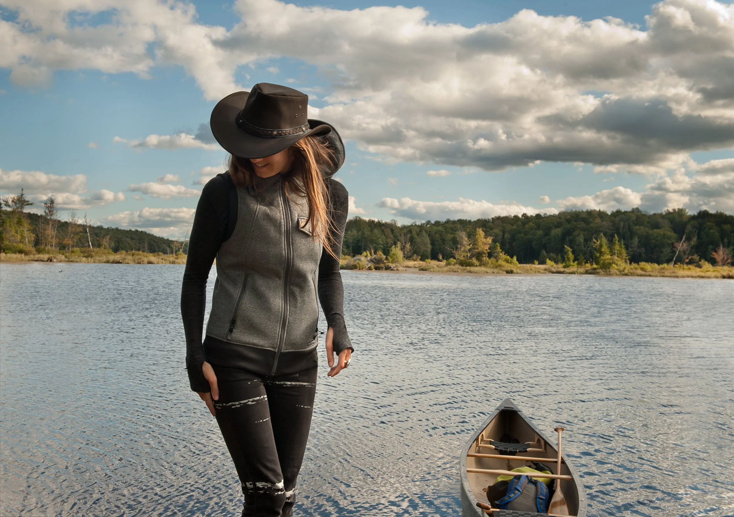 woman wearing full brimmed hat gets out of canoe at green river reservoir in vermont
