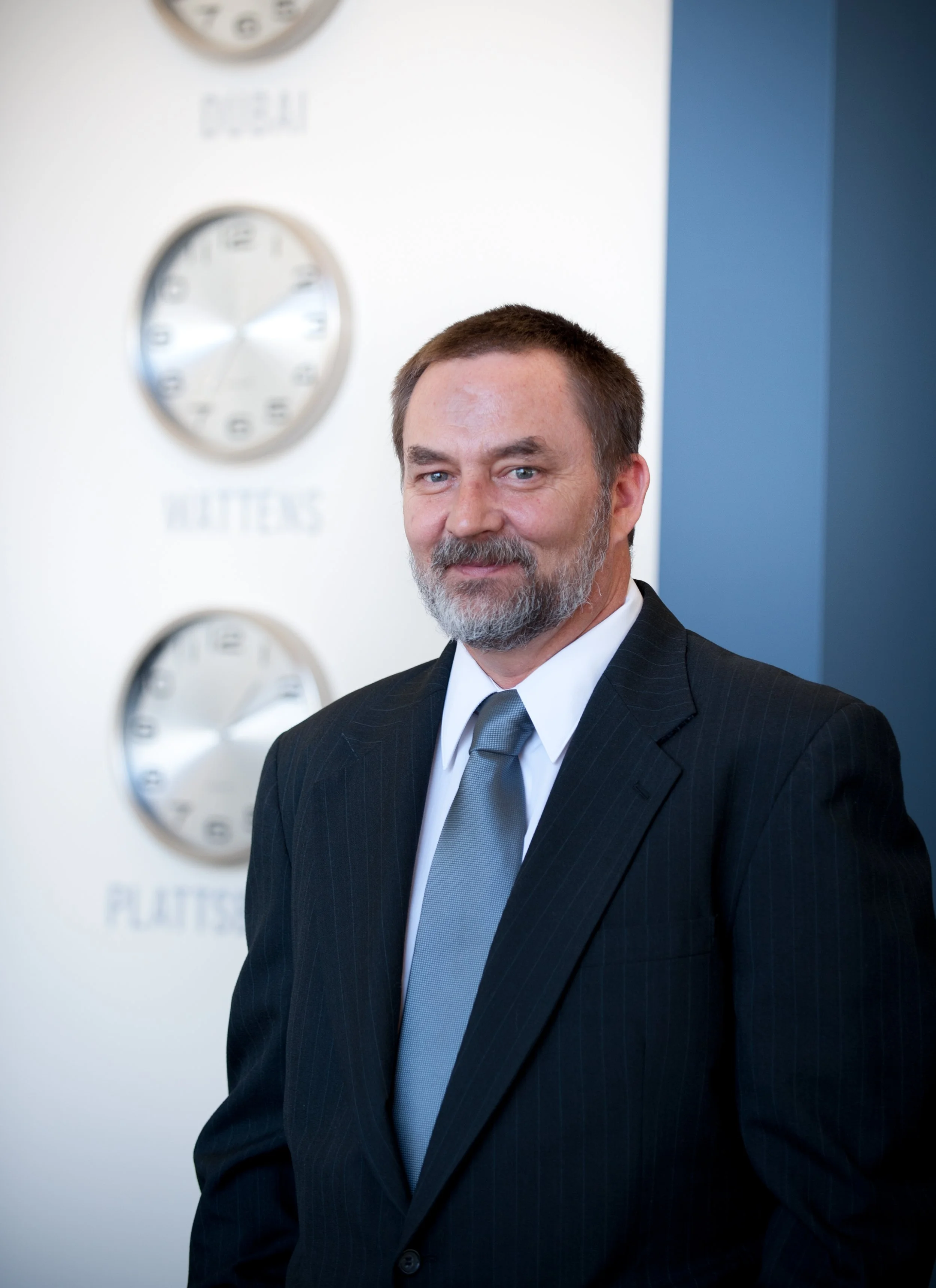 swarovski lighting executive poses for portrait in front of clocks that show times around the world