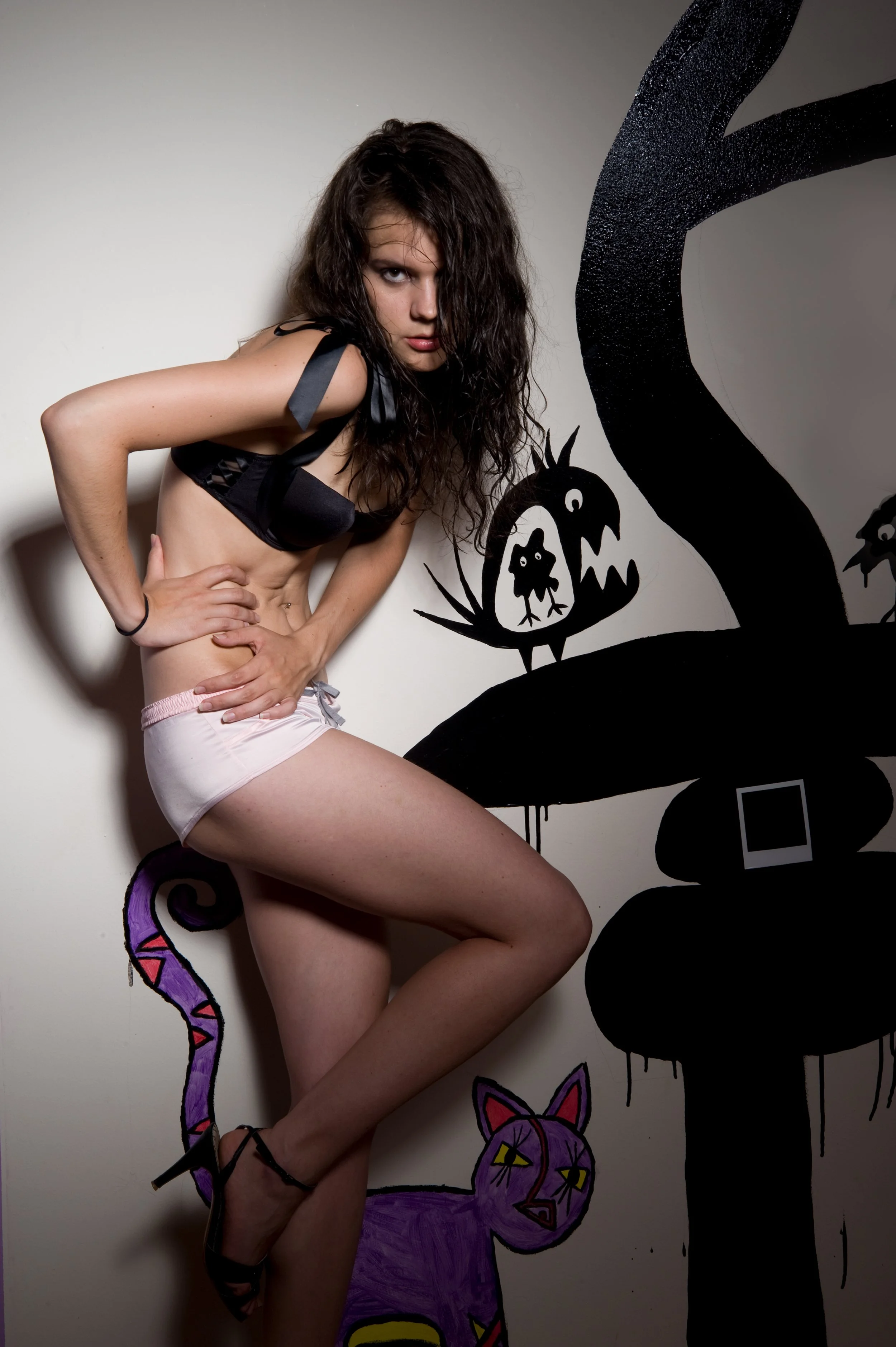 fashion model wearing black bra and pink shorts in front of mural 