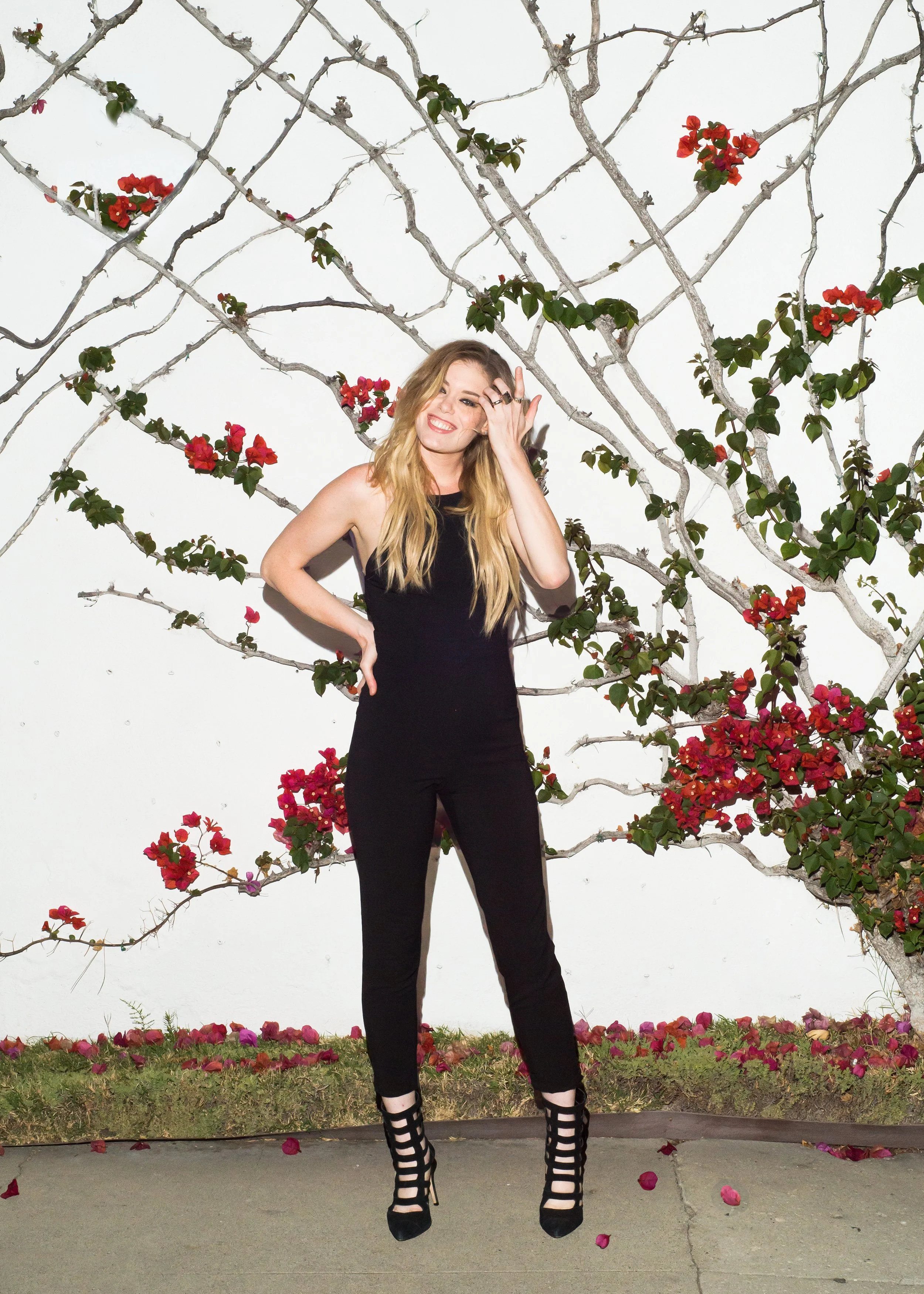 fashion photo of woman dressed in black in front of white wall with flower vines