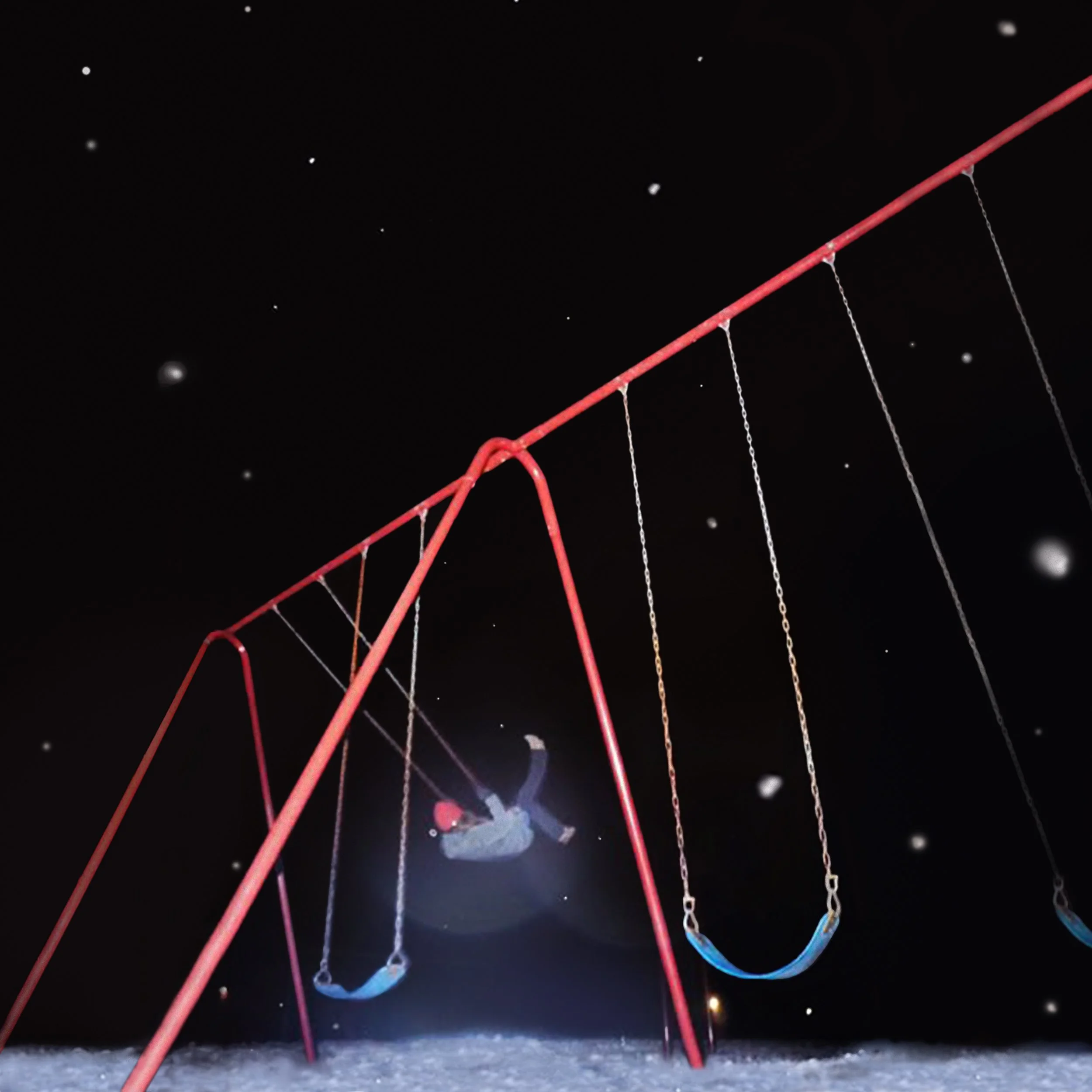 woman plays on red swingset at night while snow falls