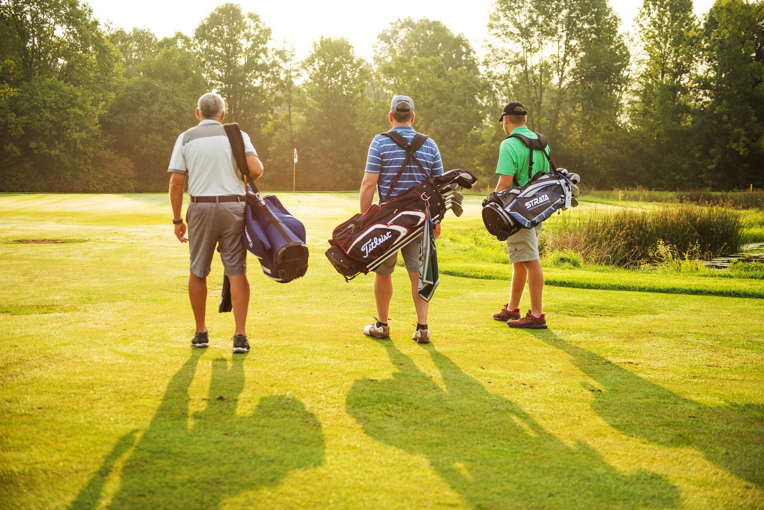 lifestyle photography of three men golfing at sunrise at basin harbor club vermont