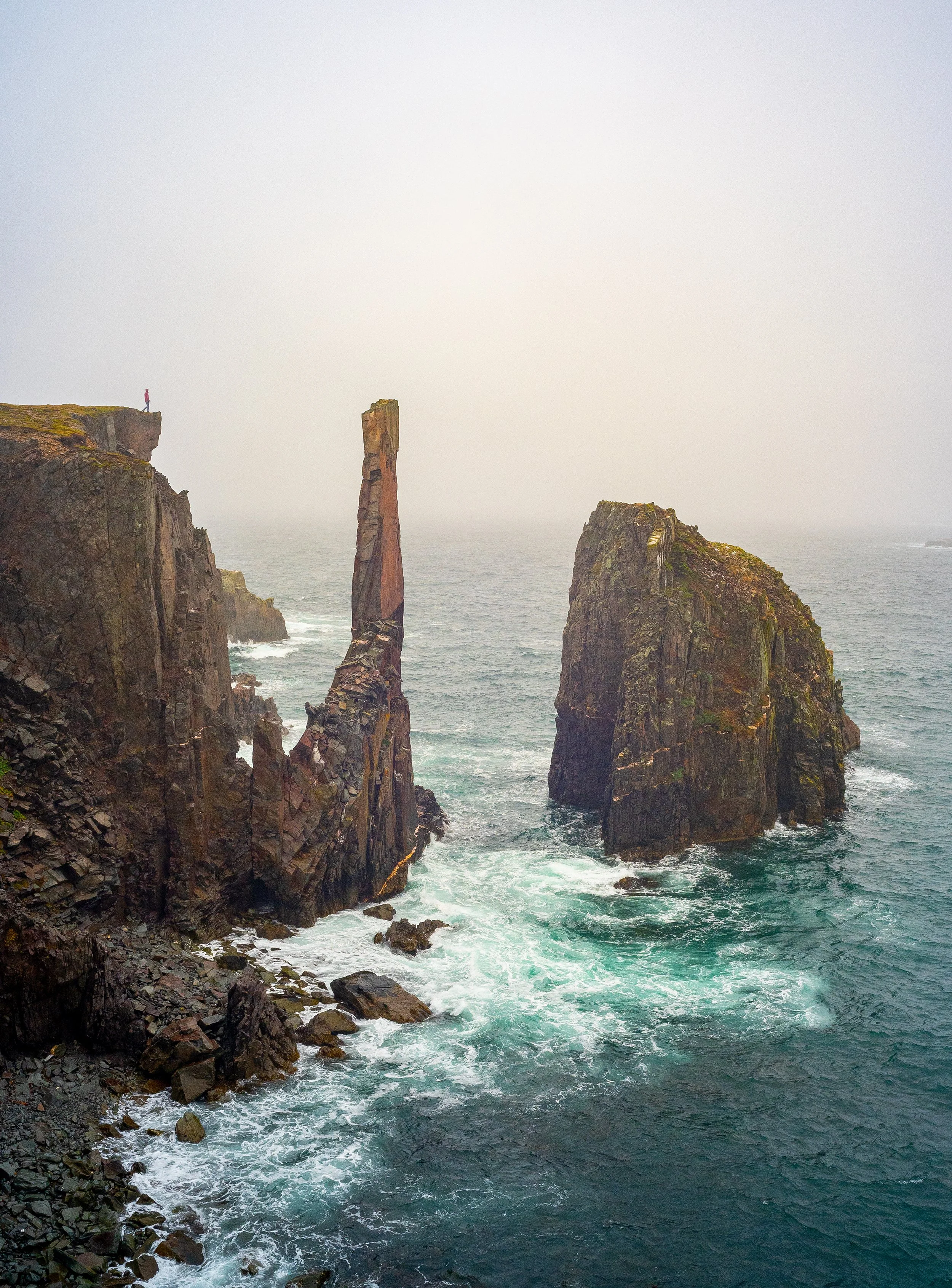 travel photography of a woman standing near the edge of a cliff at spillars cove in newfoundland