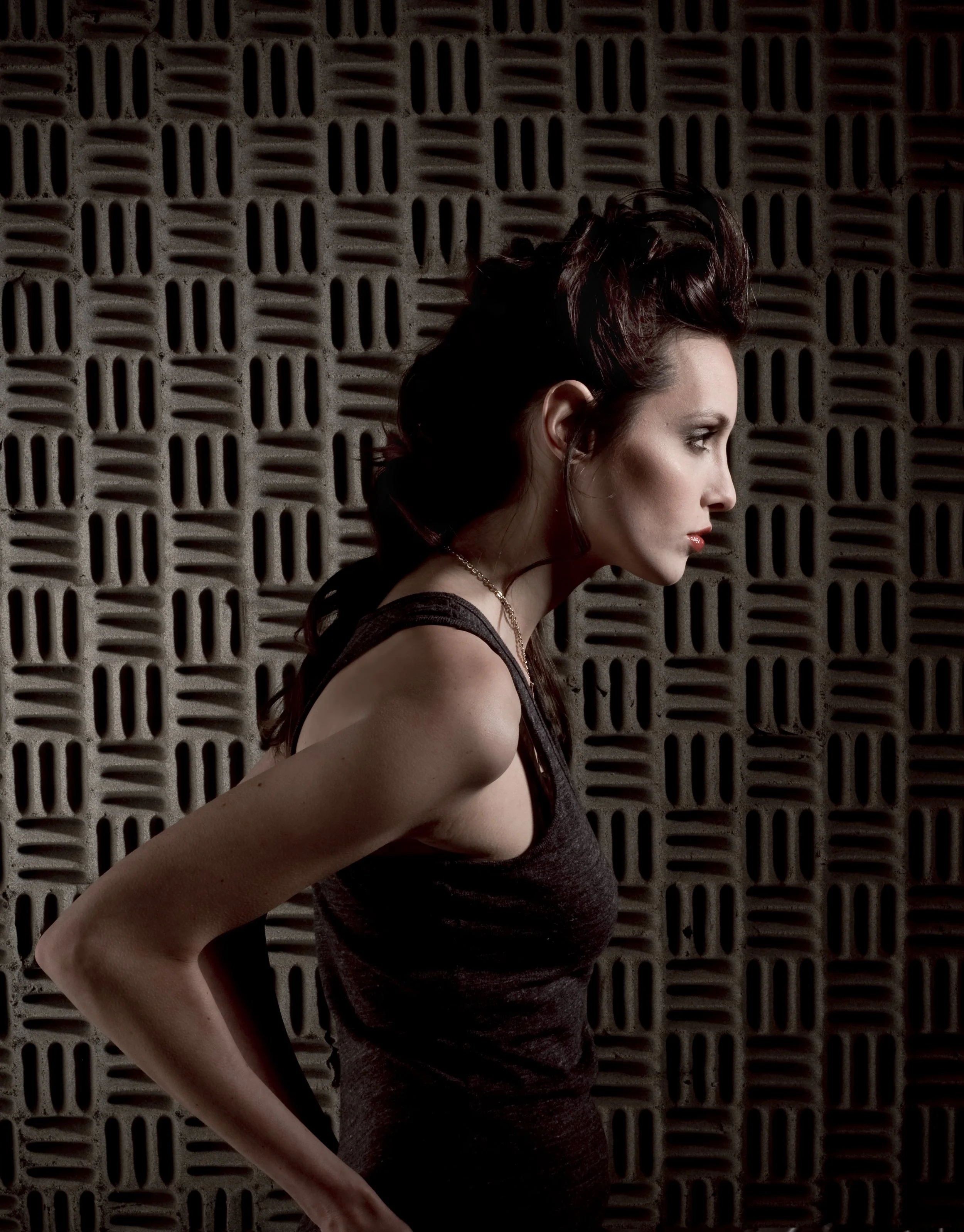 fashion photo of woman in profile standing in front of soundproofing foam panel