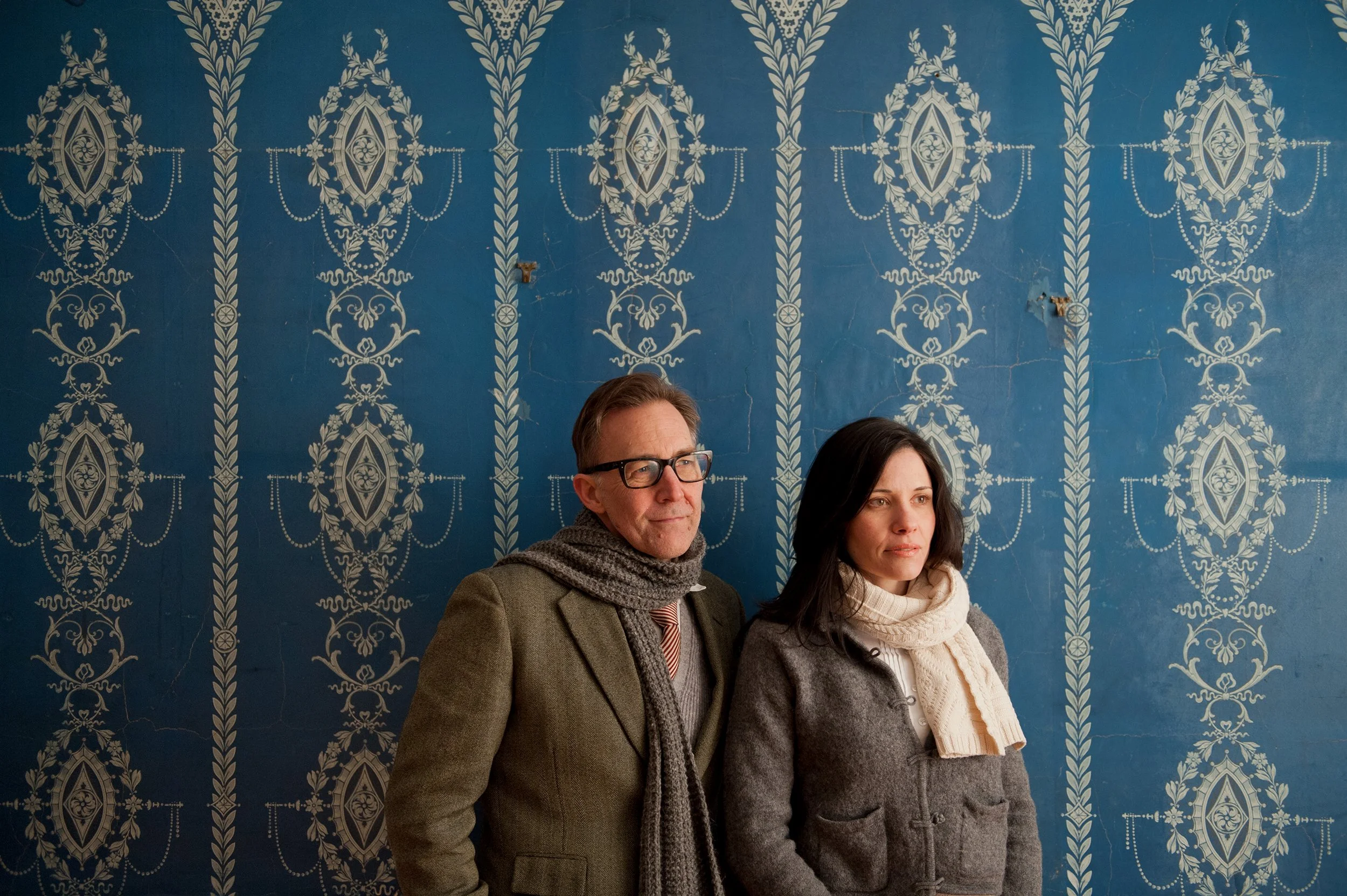 musicians shannon mcnally and brett hughes pose in front of andtique blue and white wallpaper in shelburne vermont