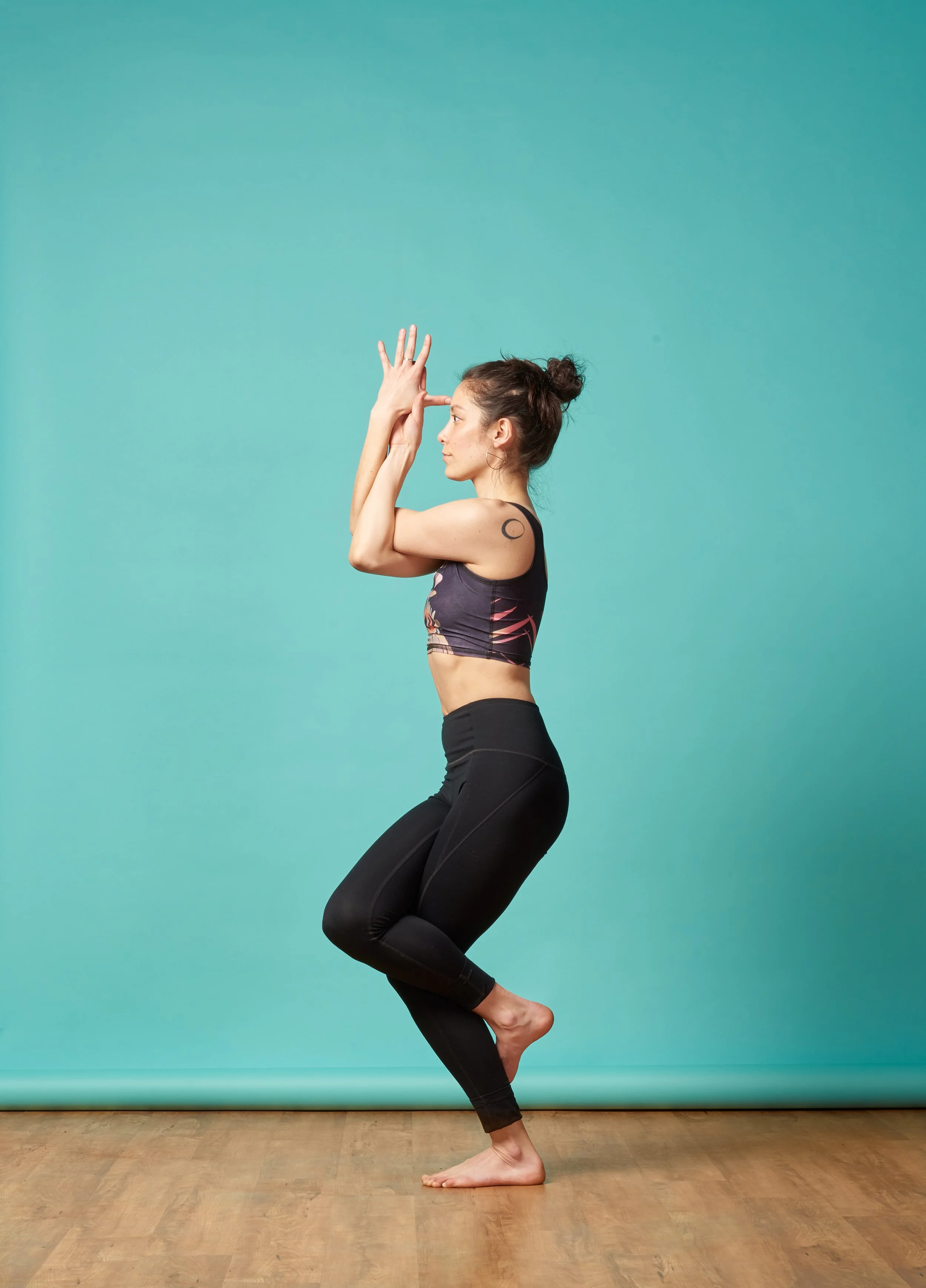 woman in yoga pose in front of teal blue background