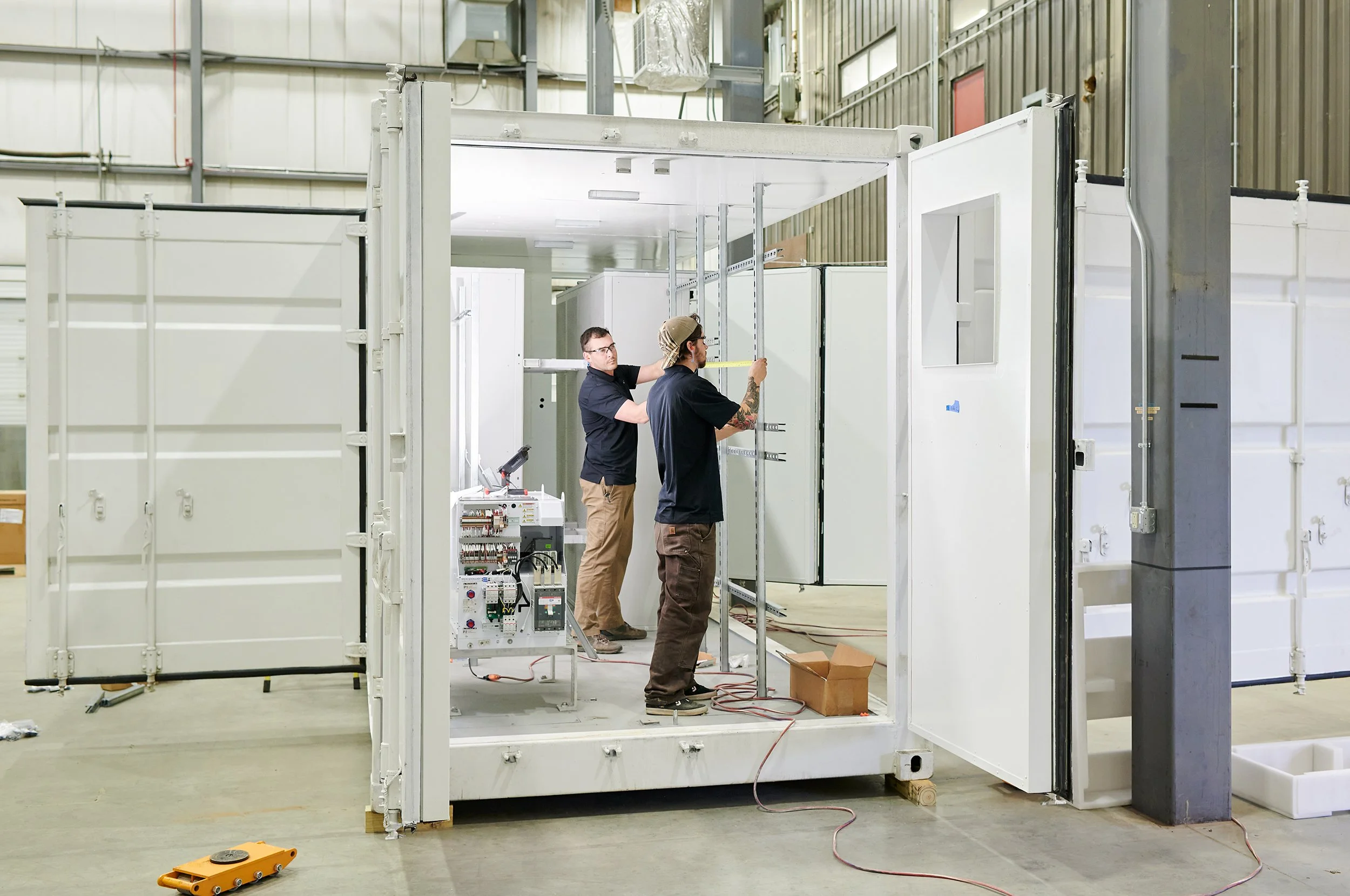 two men work on a container for high tech equipment