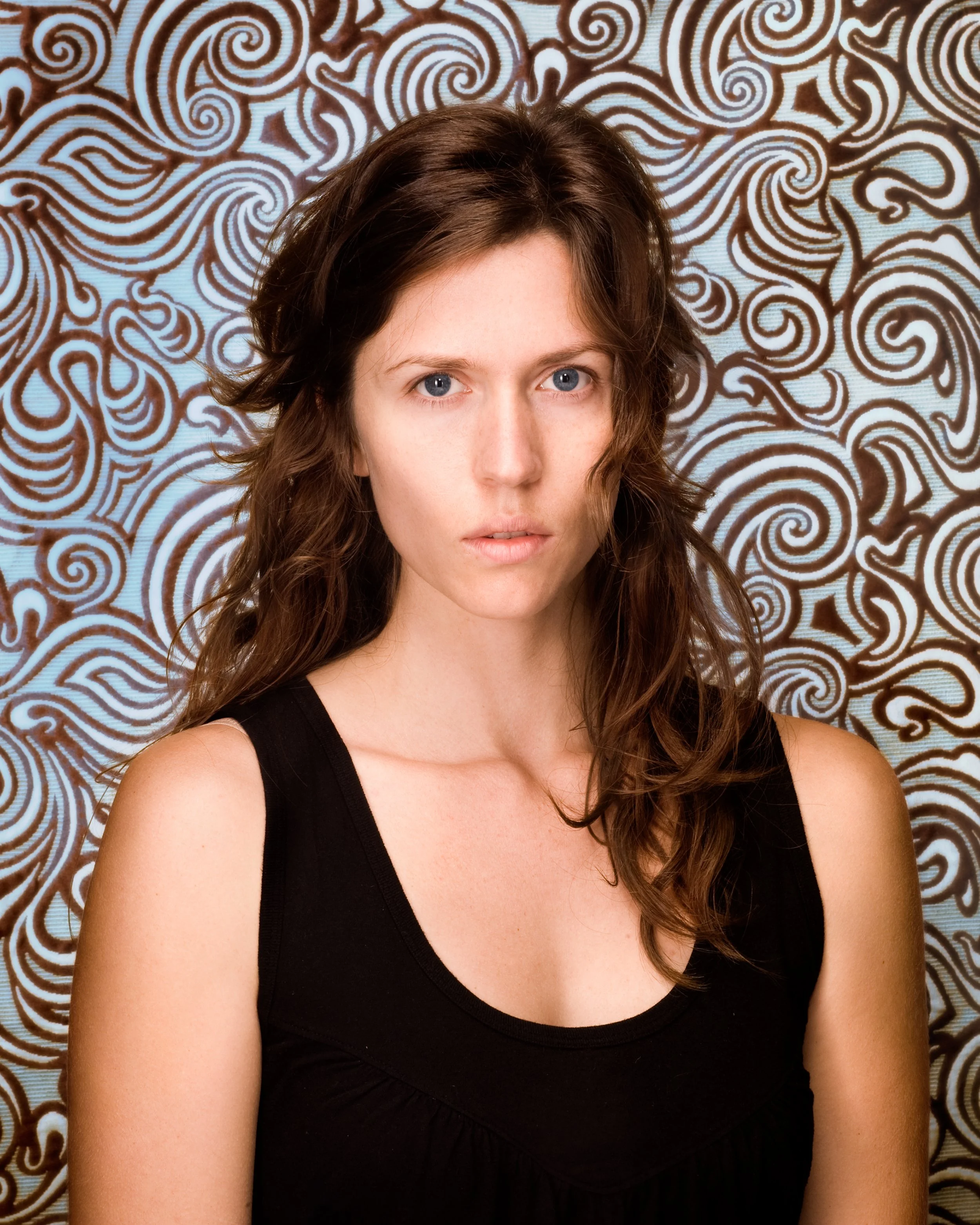 studio portrait of a dark haired woman in front of swirly blue background
