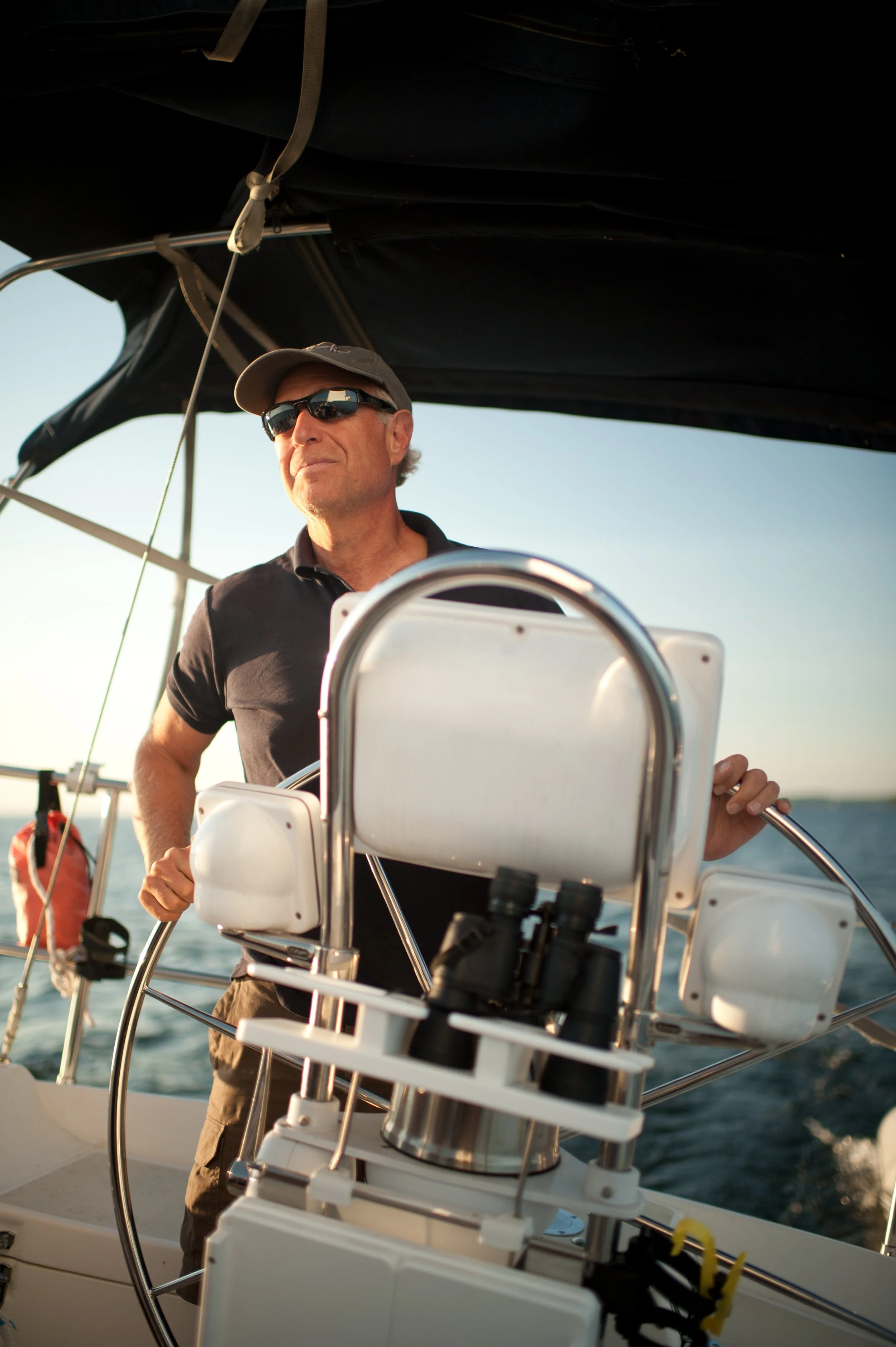 man with sunglasses at the helm of a sailboat