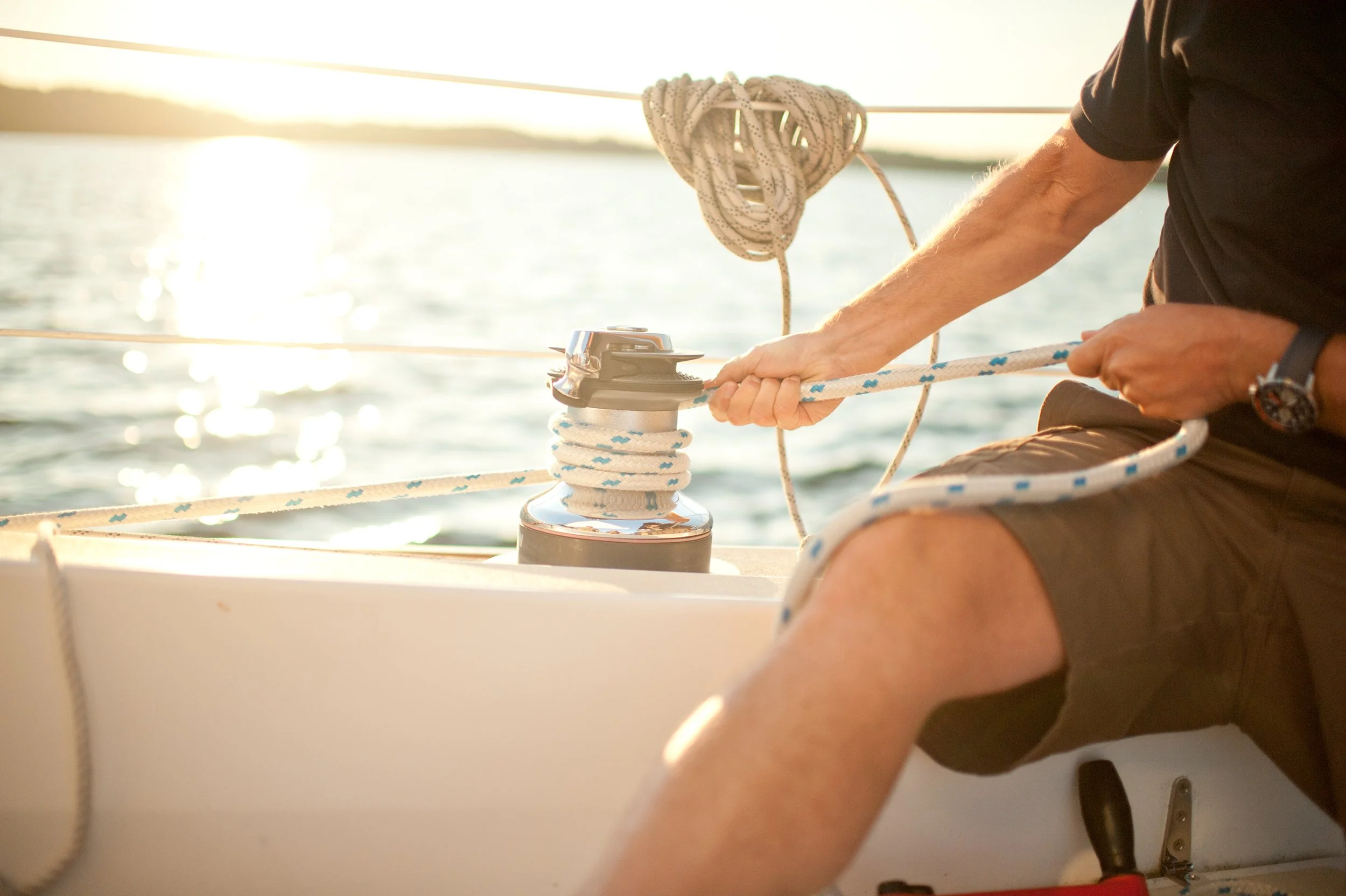 a man trims his sails at sunset on lake champlain in vermont