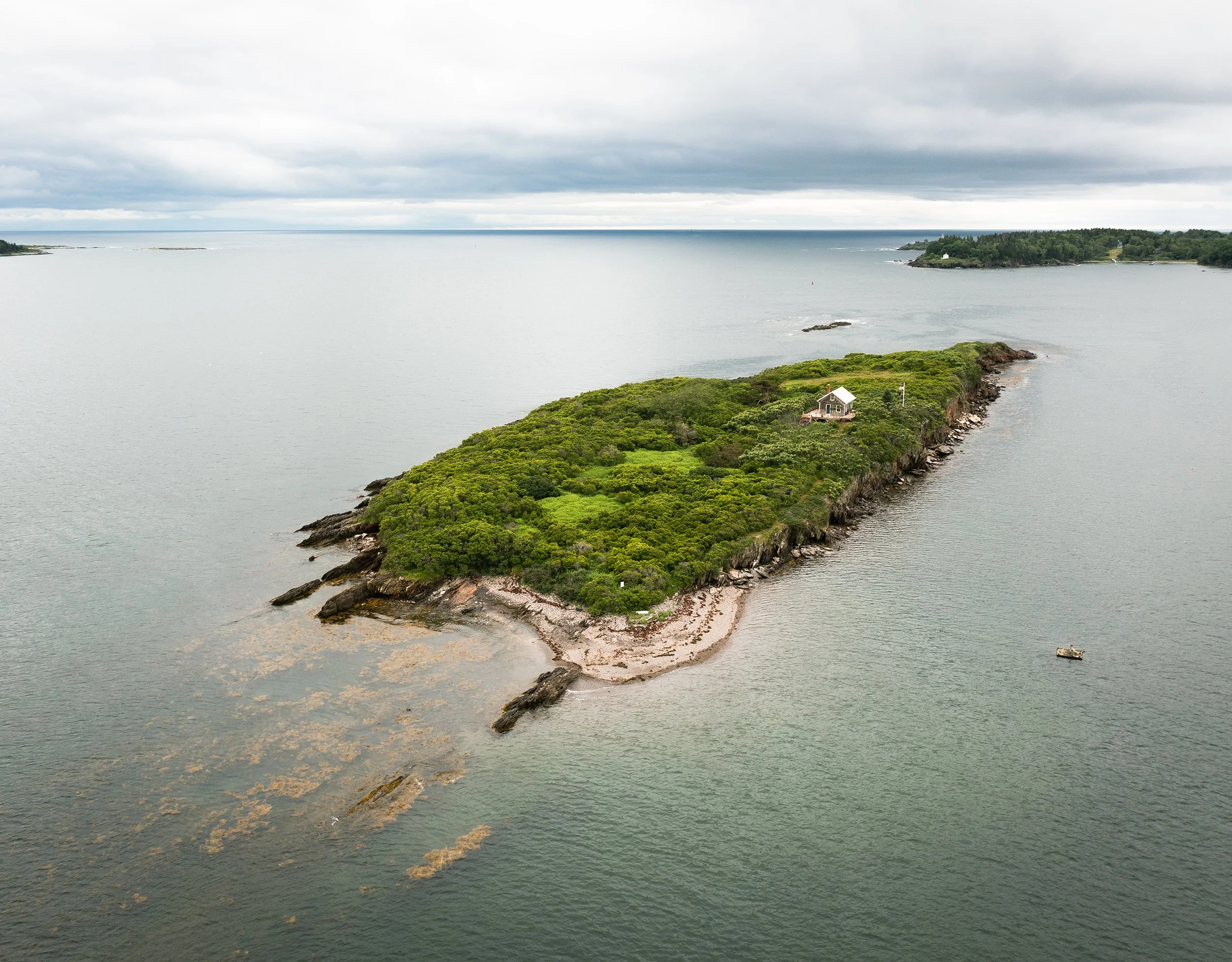aerial drone image of small island in maine with only one house on it
