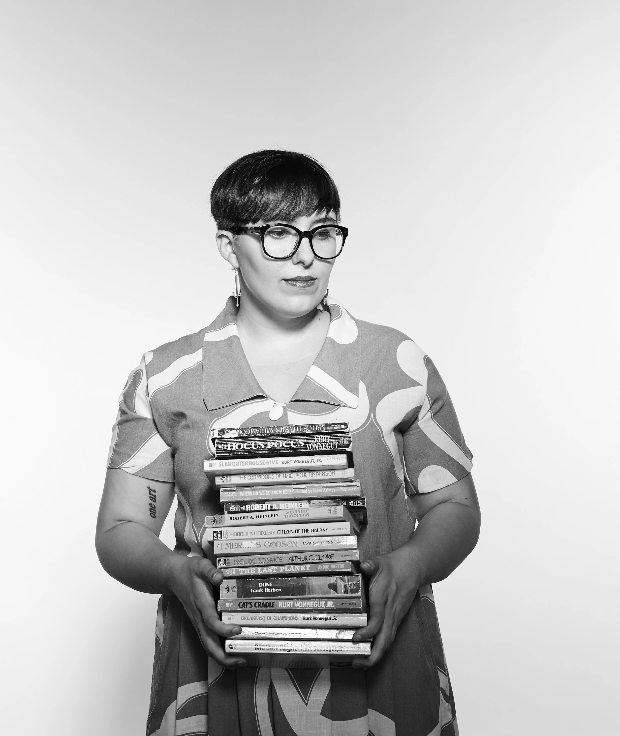 black and white photo of woman holding a stack of books