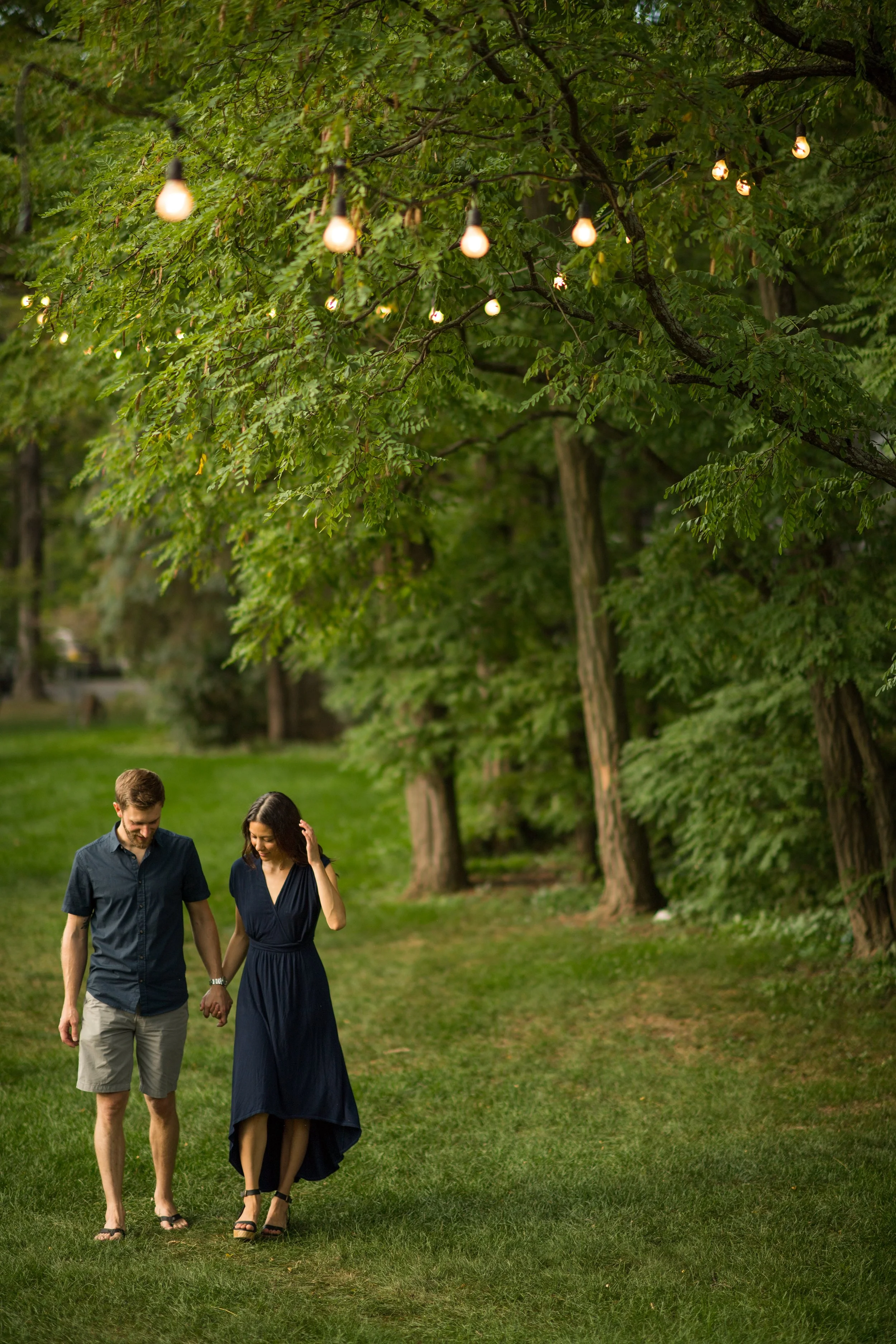 lifestyle photography of man and woman holding hands while walking through green field at dusk in vt