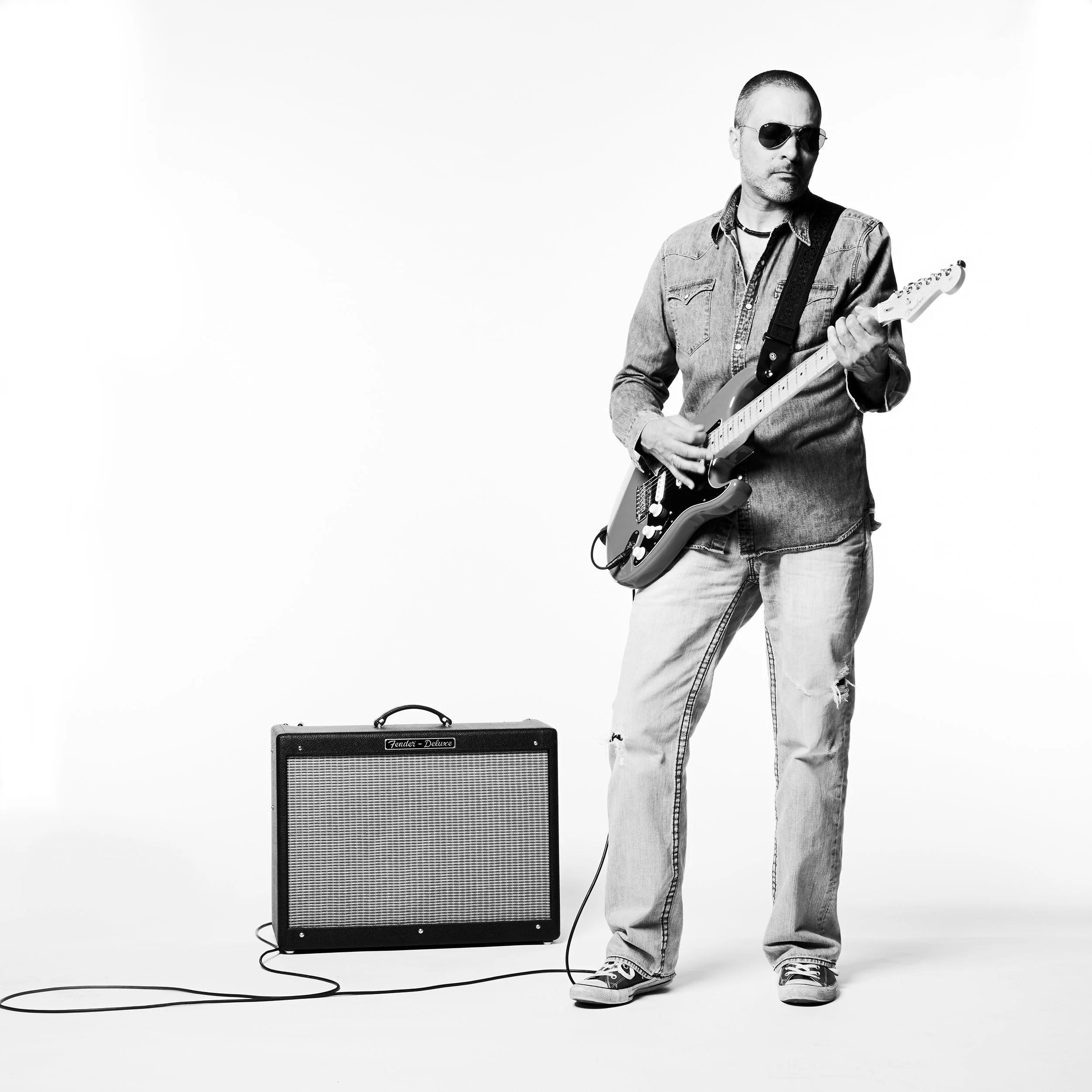 black and white portrait of a guitar playing musician with his guitar and amp