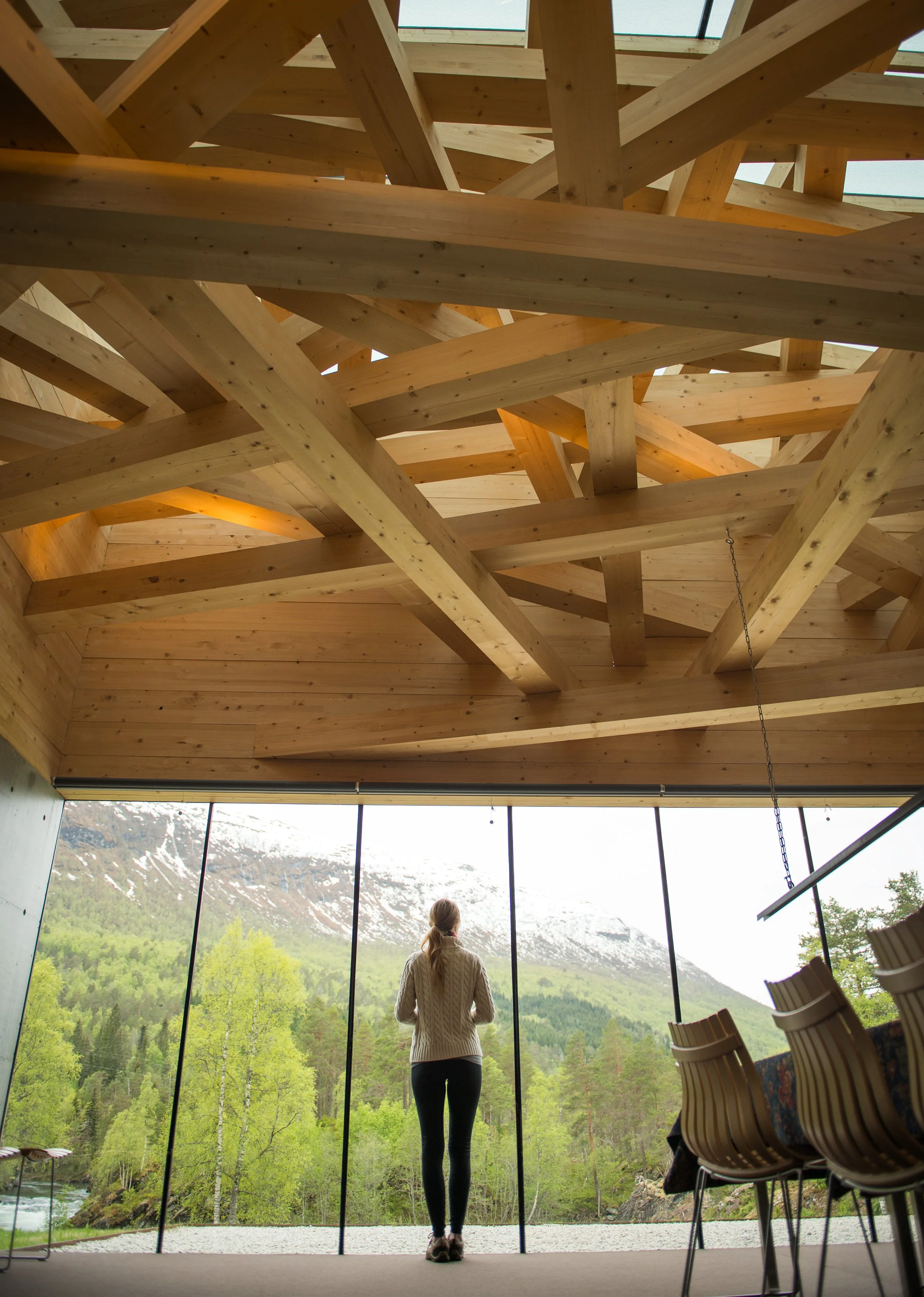 a woman looks out the windows of a room at juvet landscape hotel in norway