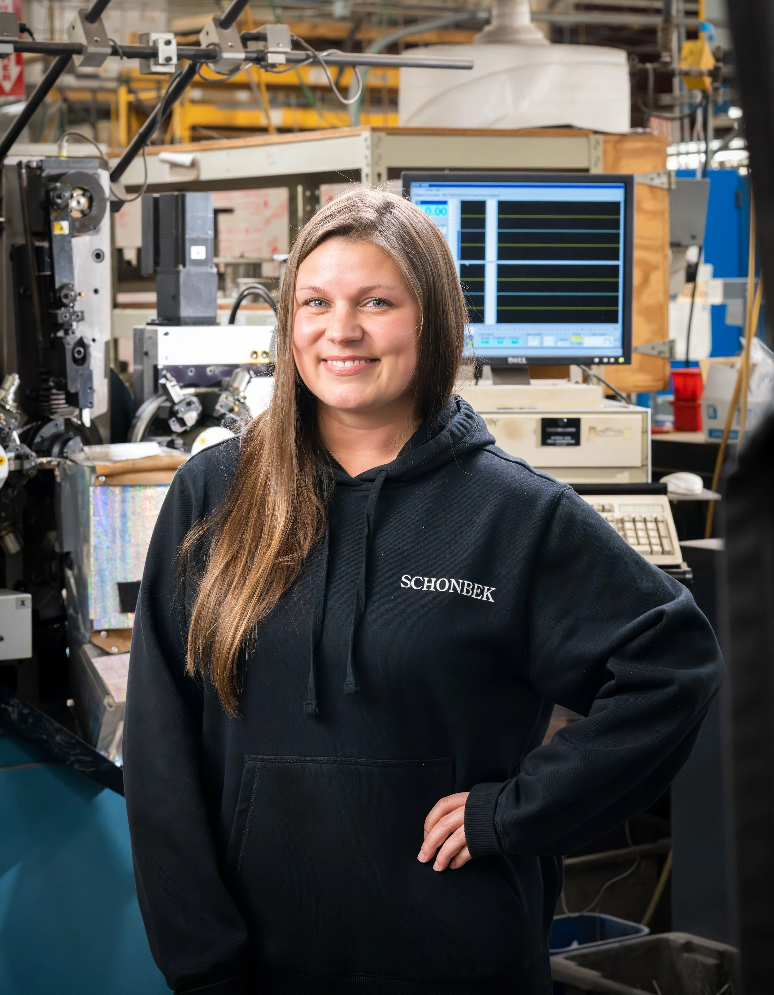 female employee at schonbek lighting smiles in front of factory machines