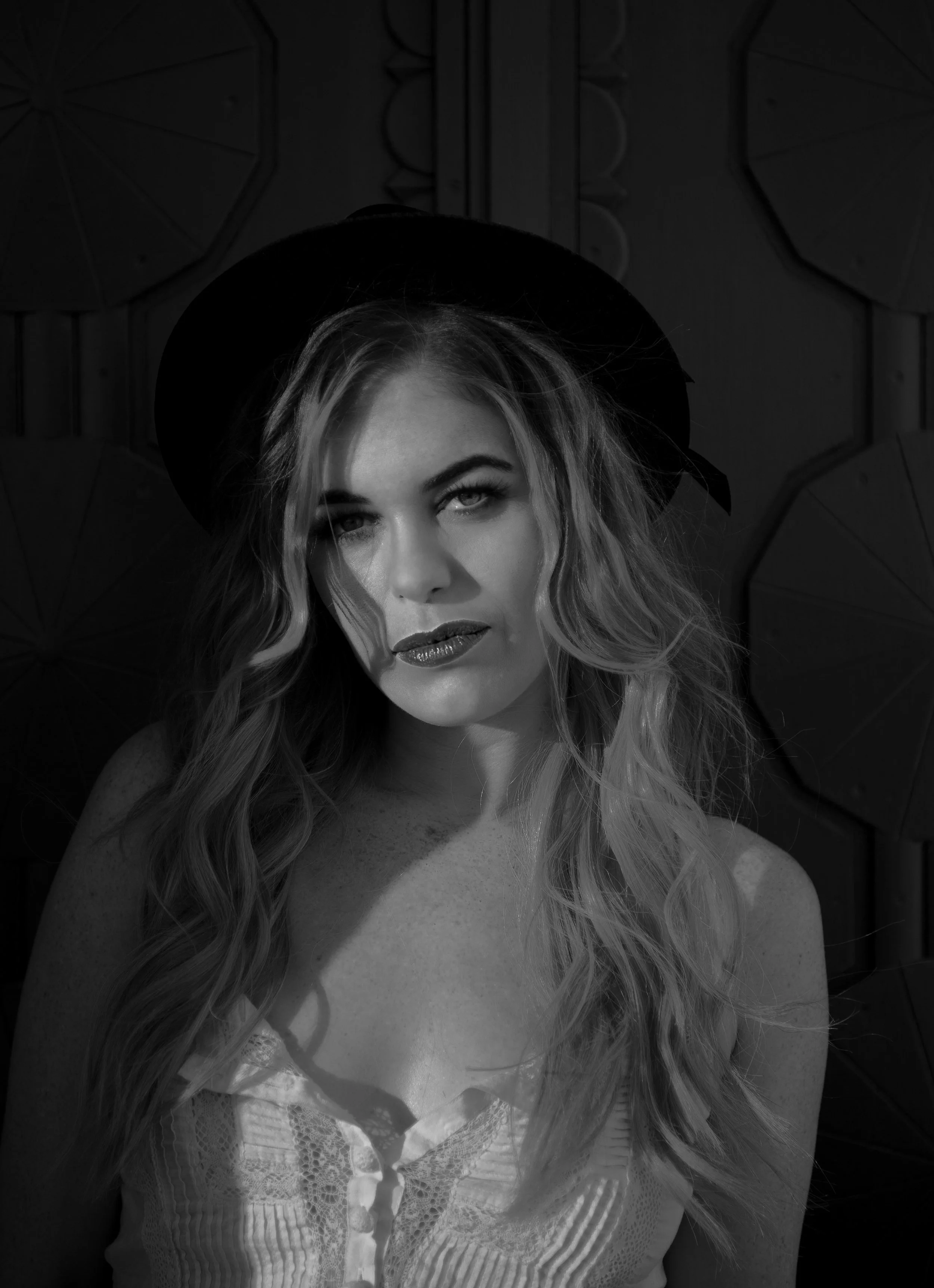 blonde haired woman wearing black full brimmed hat posing for a fashion photo shoot