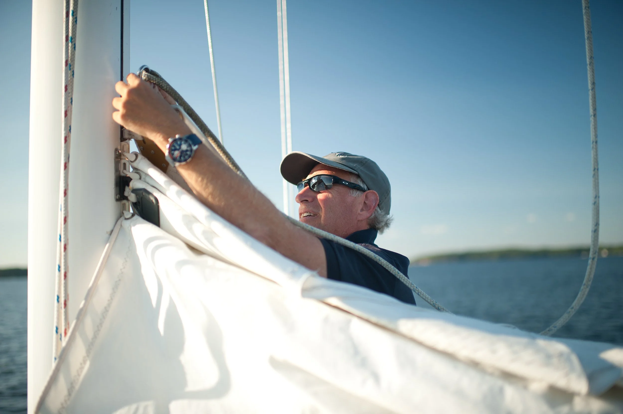 man getting the sail on his sailboat ready 