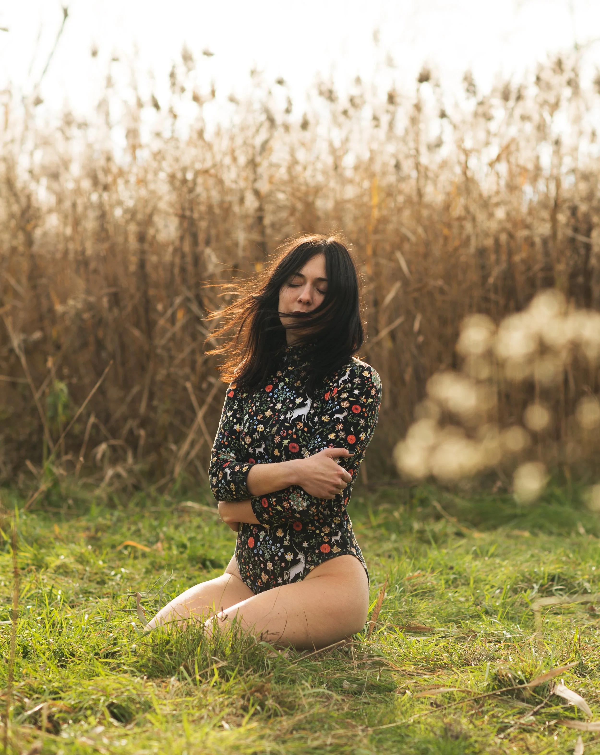 fashion photography of woman in black bodysuit kneeling in a field of grass taken in Burlington vermont
