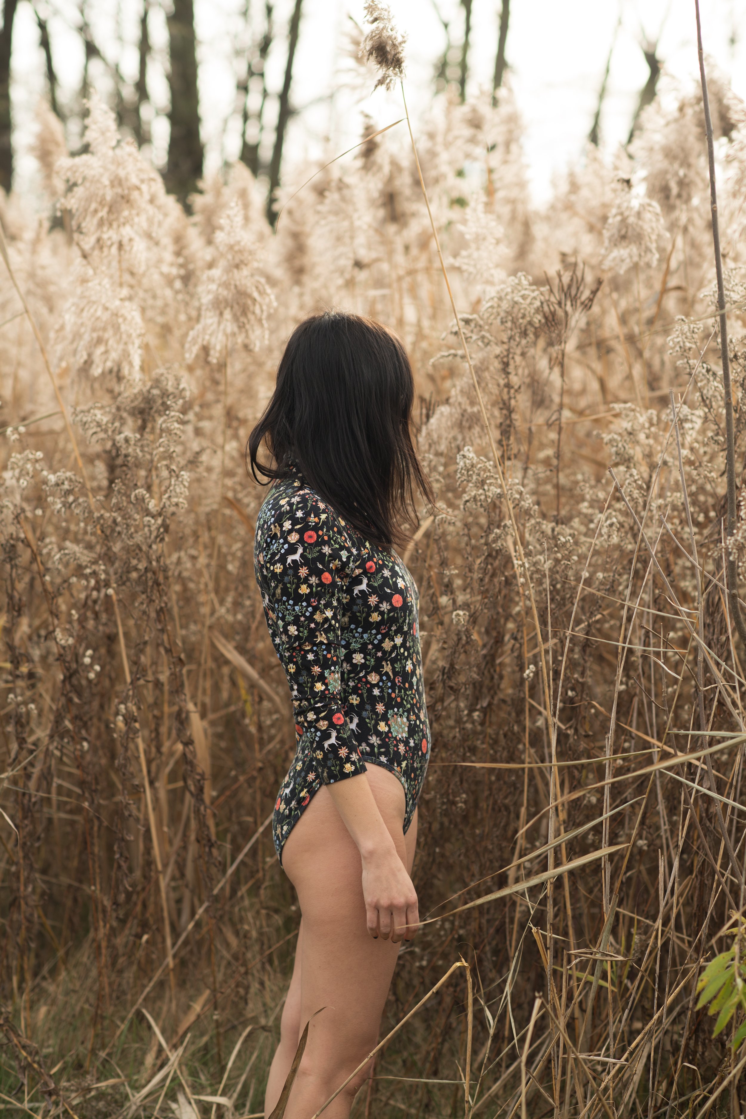 Burlington vermont fashion photography of  amanda richer in a patterned black bodysuit while she stands in reeds 
