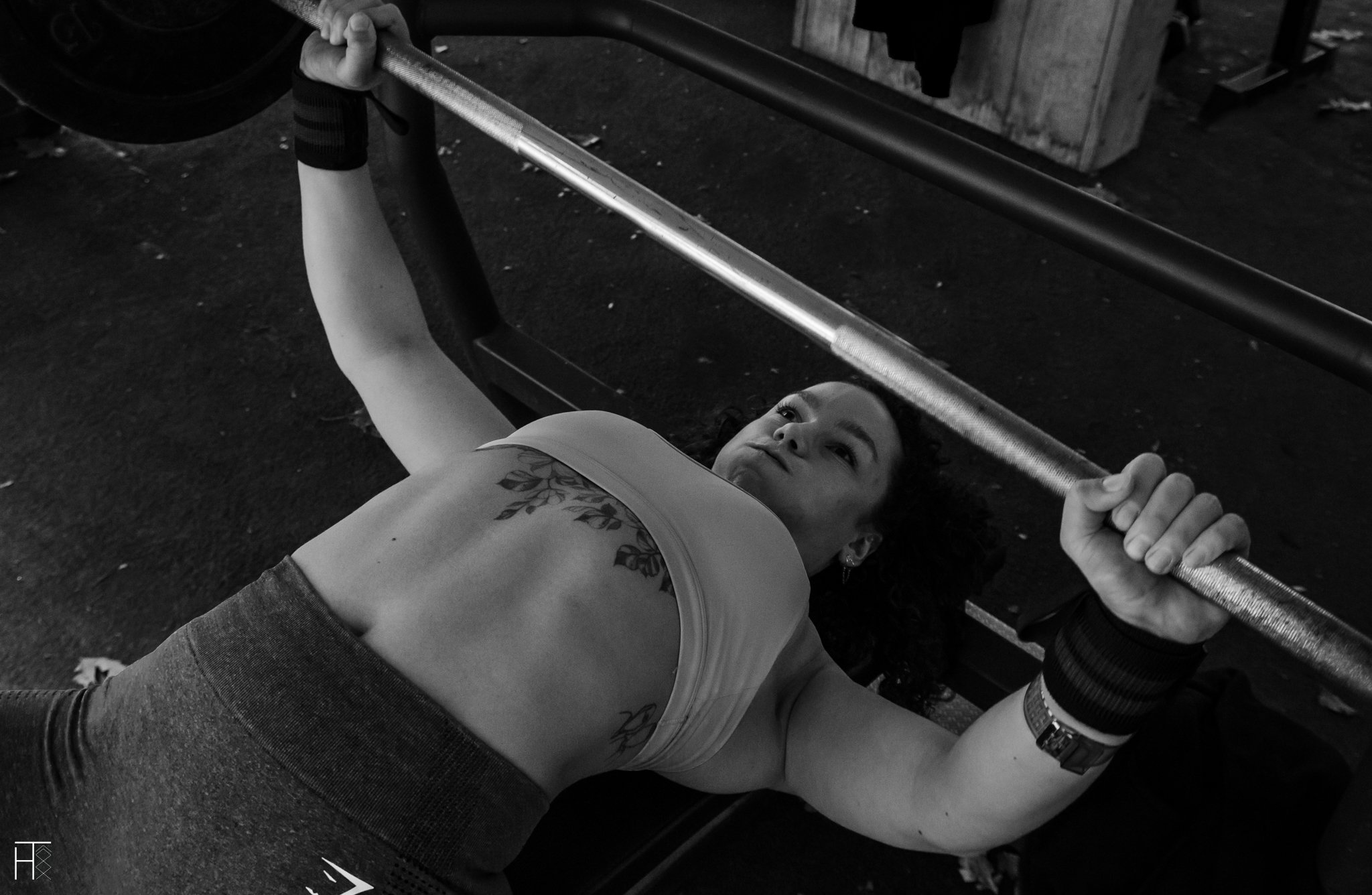 Person performing bench press exercise with a barbell, wearing workout clothing.