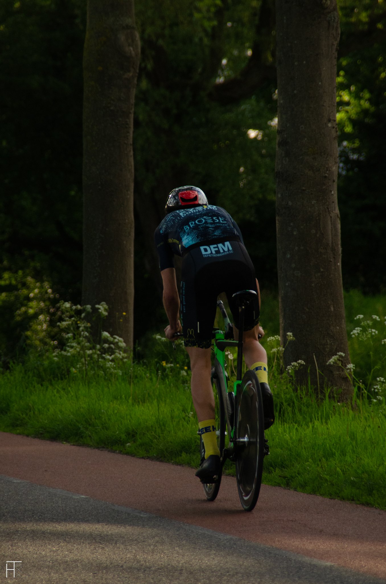 Cyclist in helmet riding a time trial bike on a wooded road