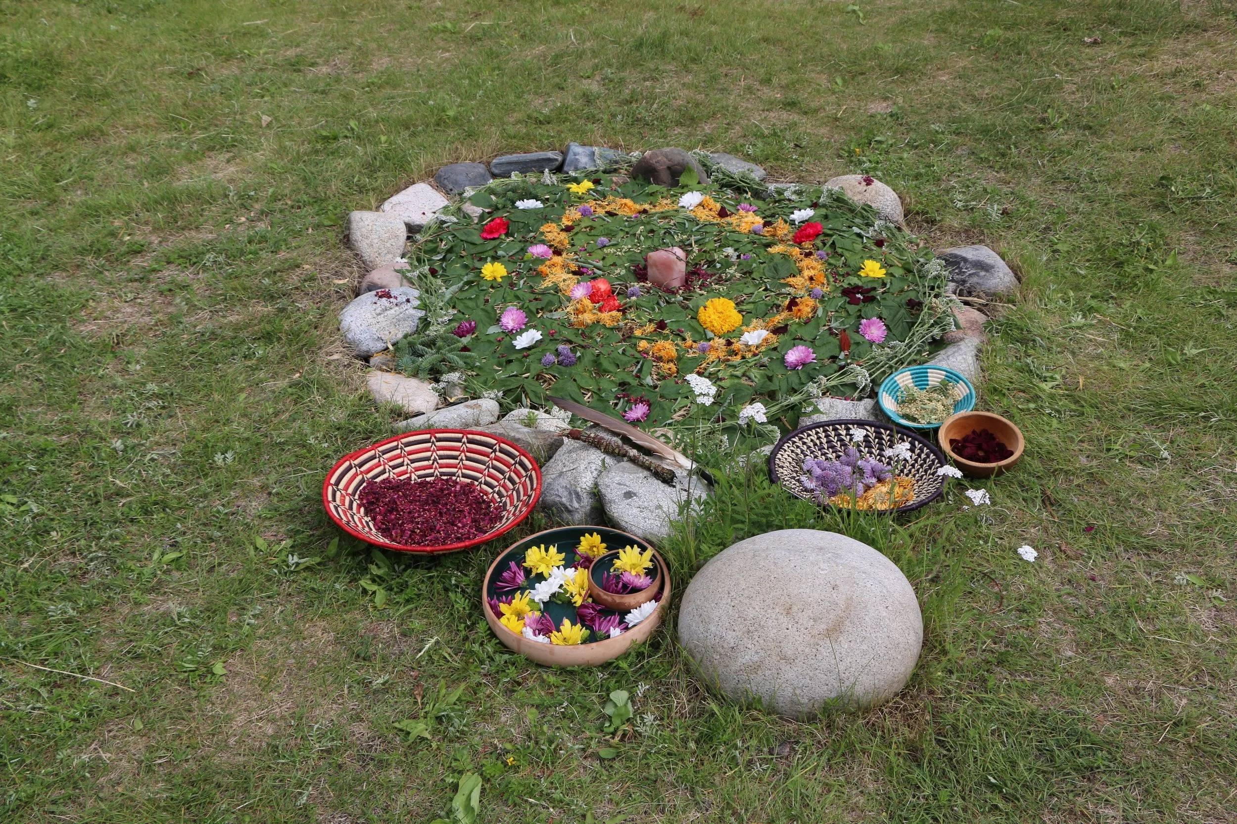 mandala made of flowers and plant materials within a rock circle