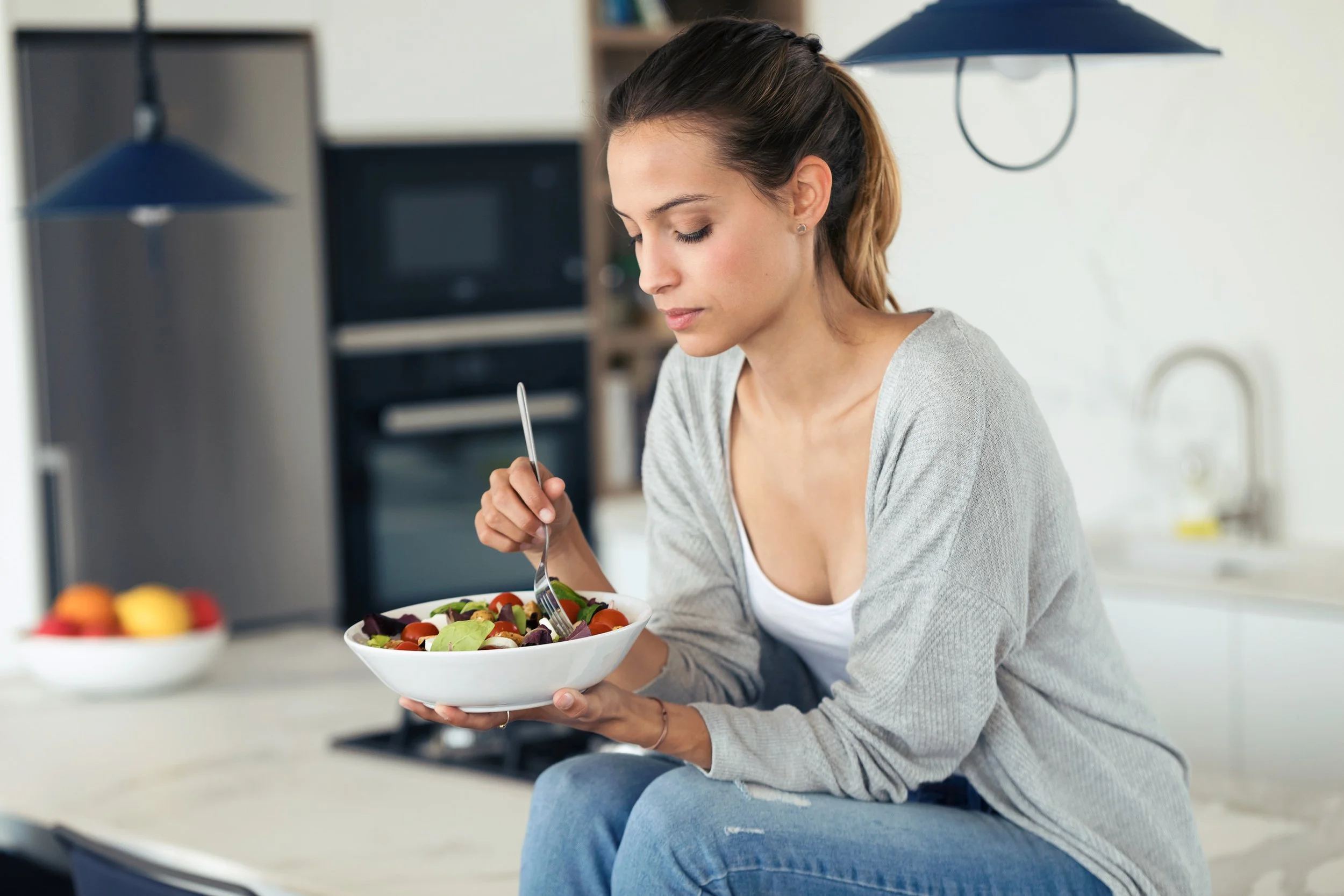 A woman focused on her bowl of healthy food, reflecting the Awareness phase of the 12-Week Gut Health Program where participants explore their unique eating patterns and mindful choices.