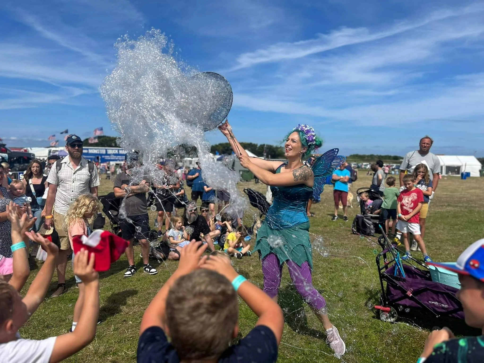 Fairy Performer creating bubbles in west field with large crowd