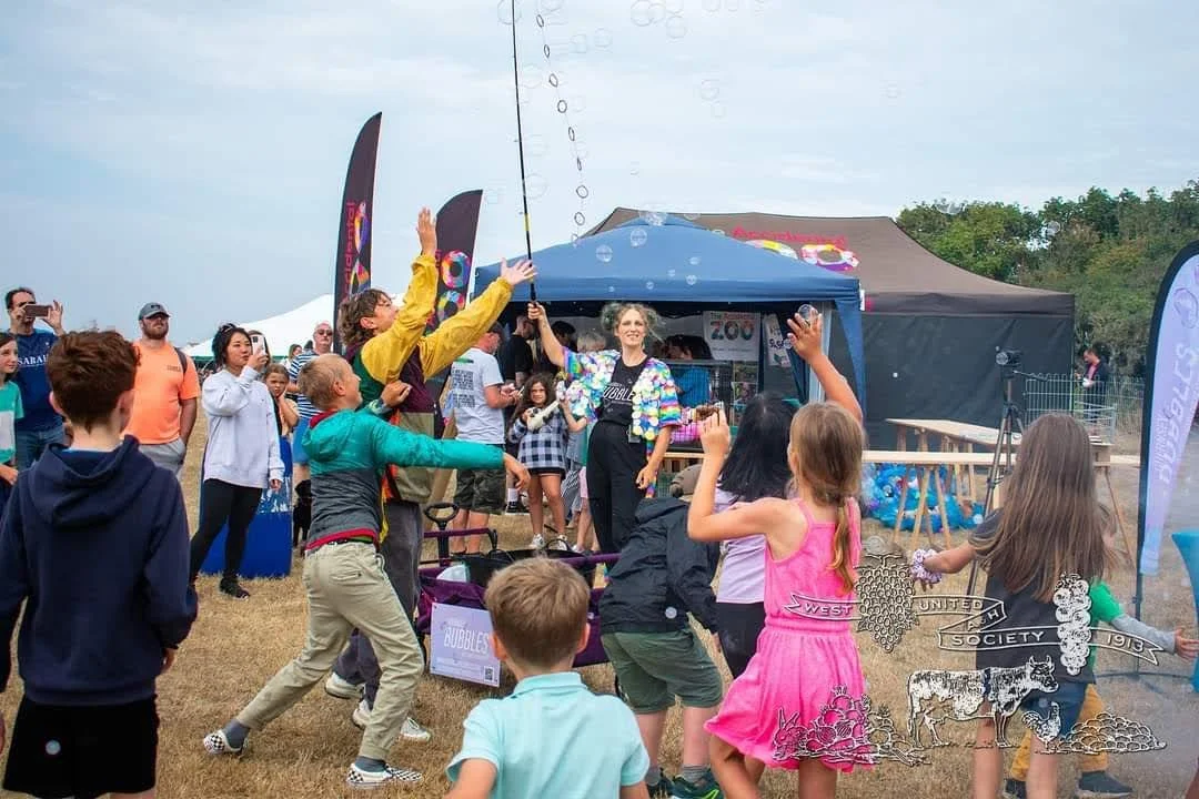Performer creating bubbles in west field with large crowd