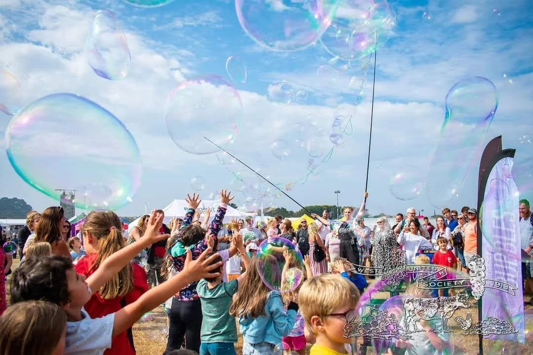 Performer creating bubbles in west field with large crowd