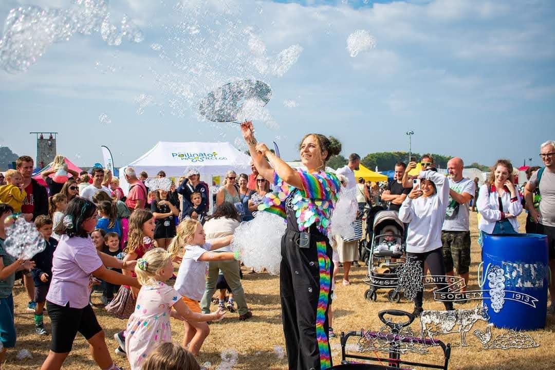 Performer creating bubbles in west field with large crowd