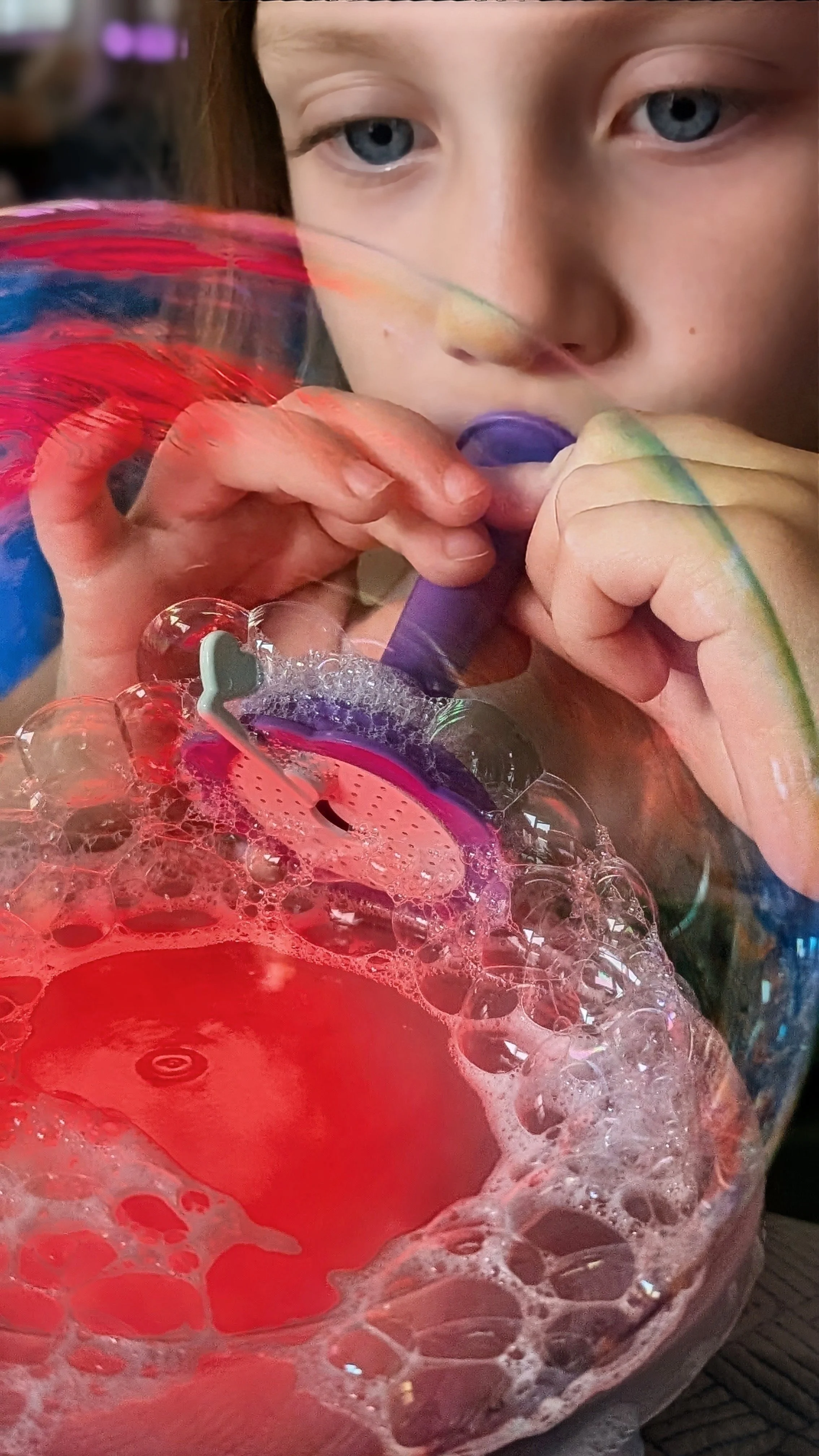 Child blowing bubble on light table with foamer