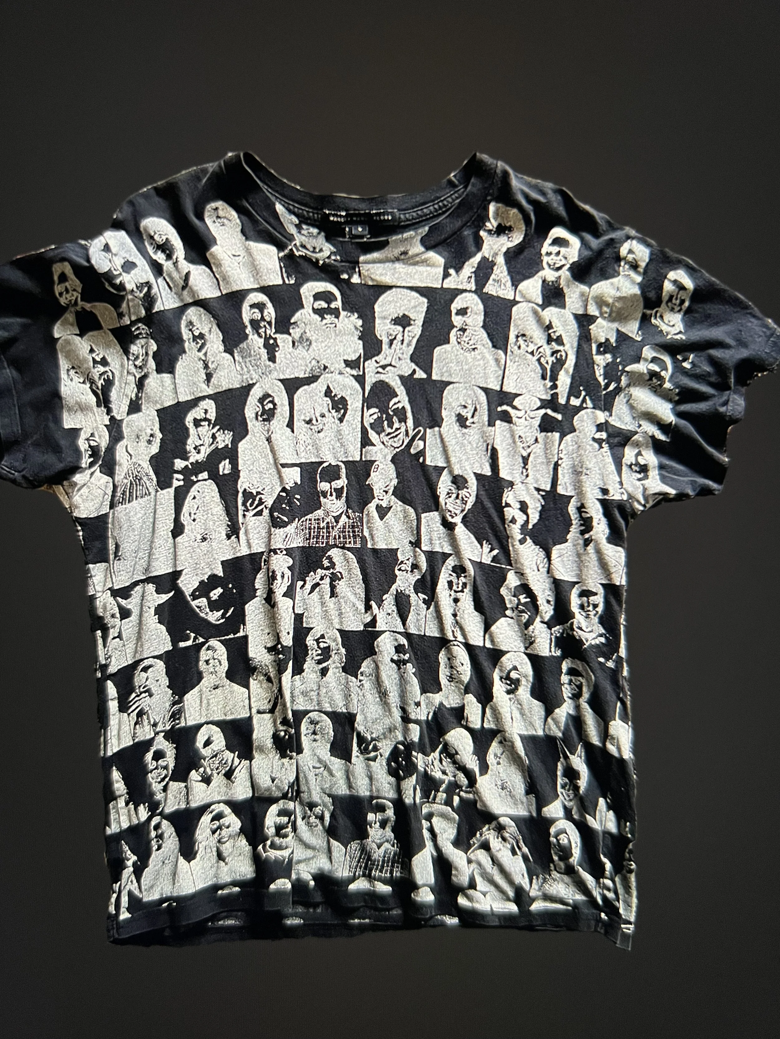 Black t-shirt with white printed images of various people in a grid pattern.