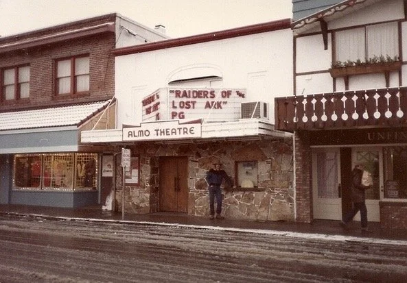 The Almo Theatre in a small town, with a marquee sign and a person standing outside.