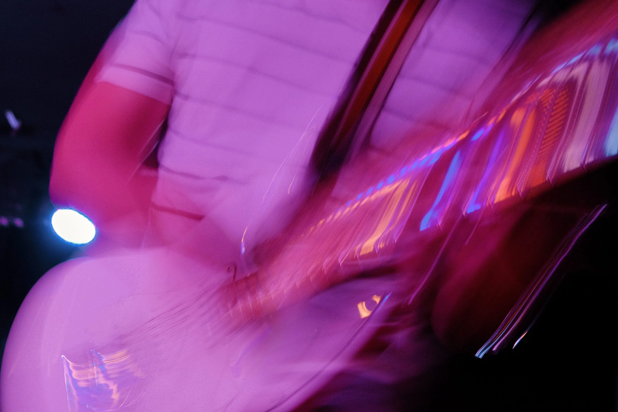 Abstract image of swirling pink and purple lights with some blue and orange reflections.