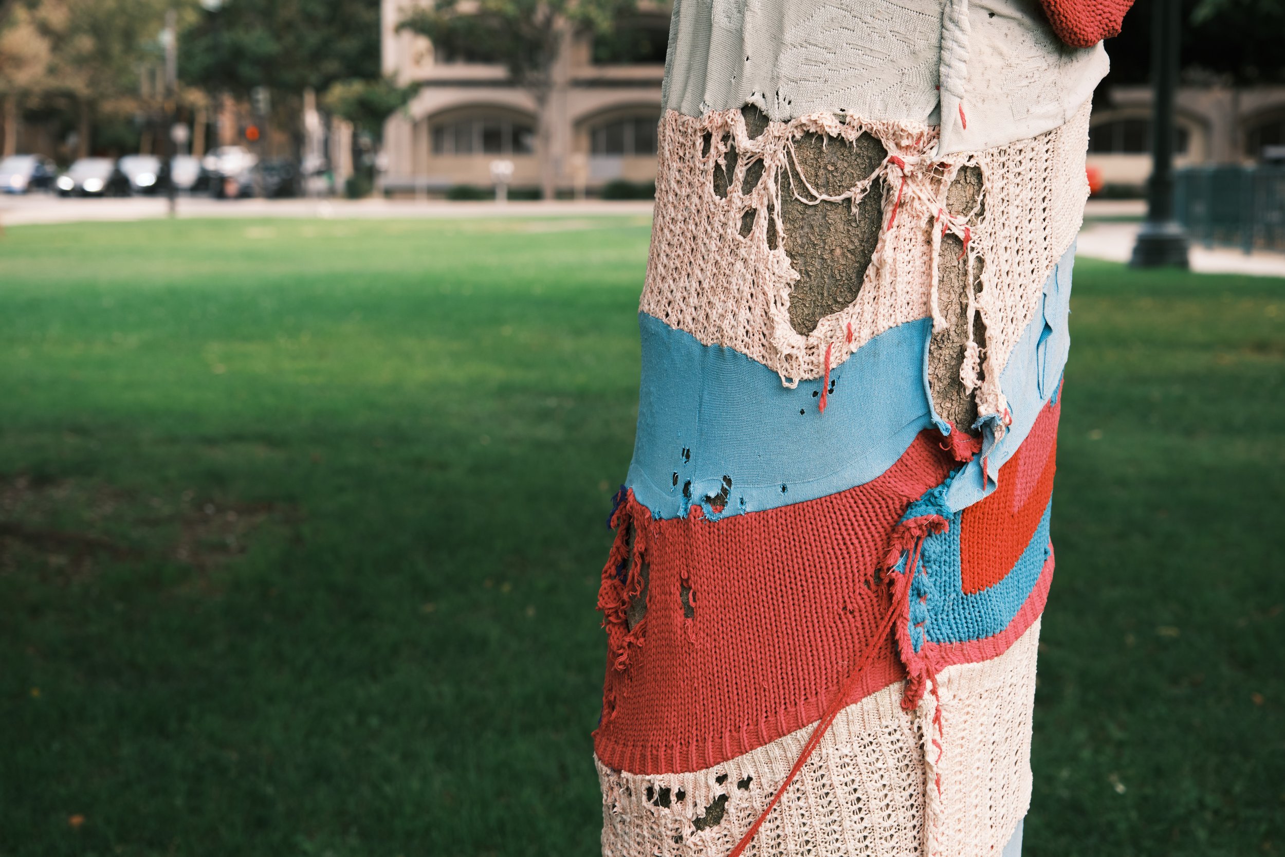Close-up of a person's colorful, distressed patchwork tree-sock made of various fabrics, with in a park setting.