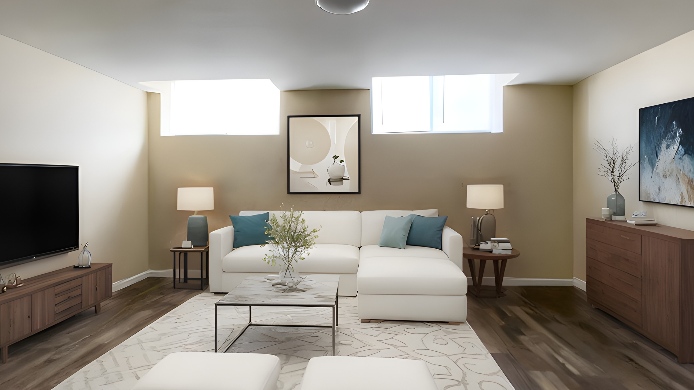 Bright living room with a white sectional sofa, blue and teal pillows, wooden coffee table, two side tables with lamps, a large flat-screen TV, a wooden sideboard, and abstract artwork on the walls.