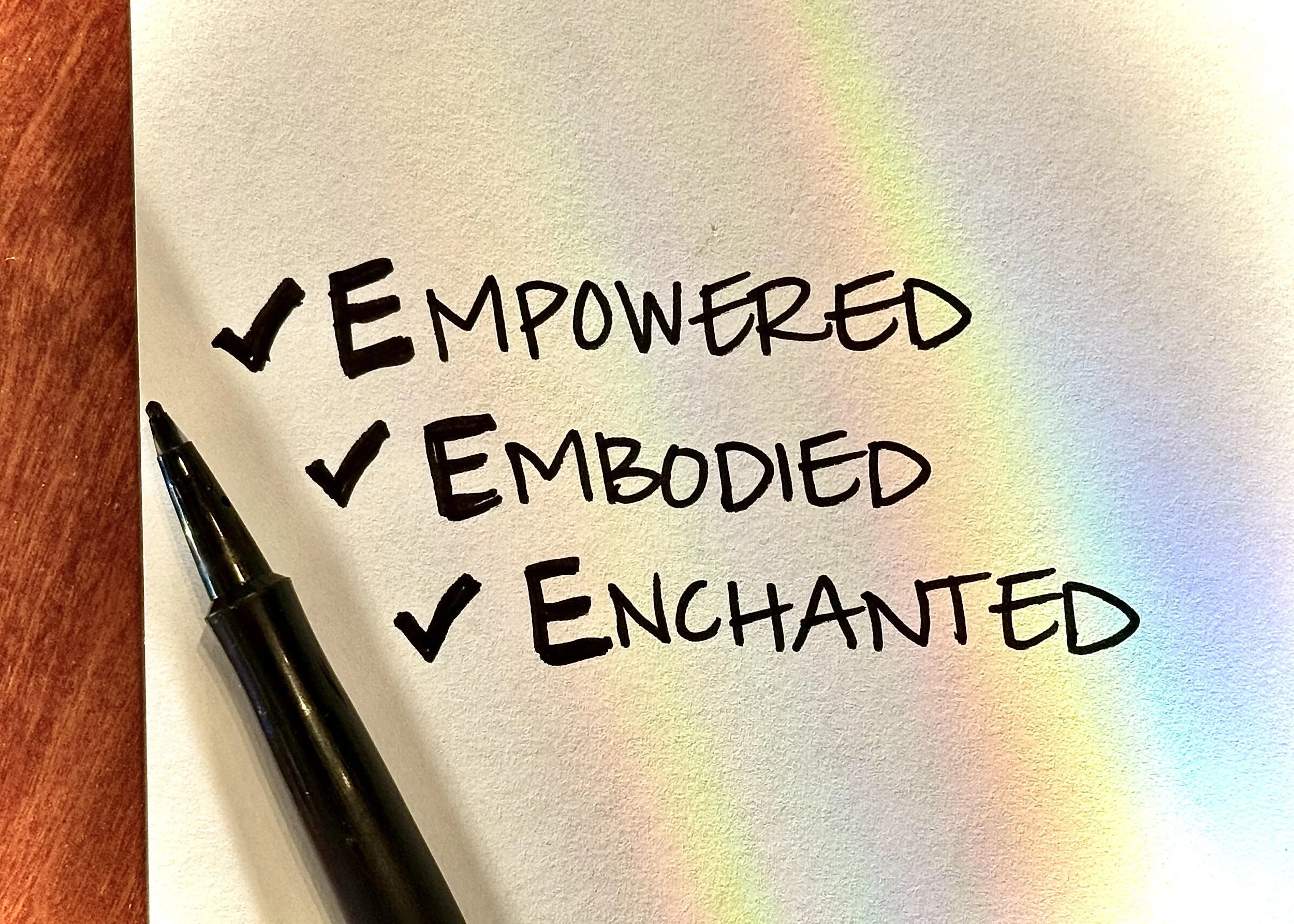 Three words written in black ink Empowered Embodied Enchanted