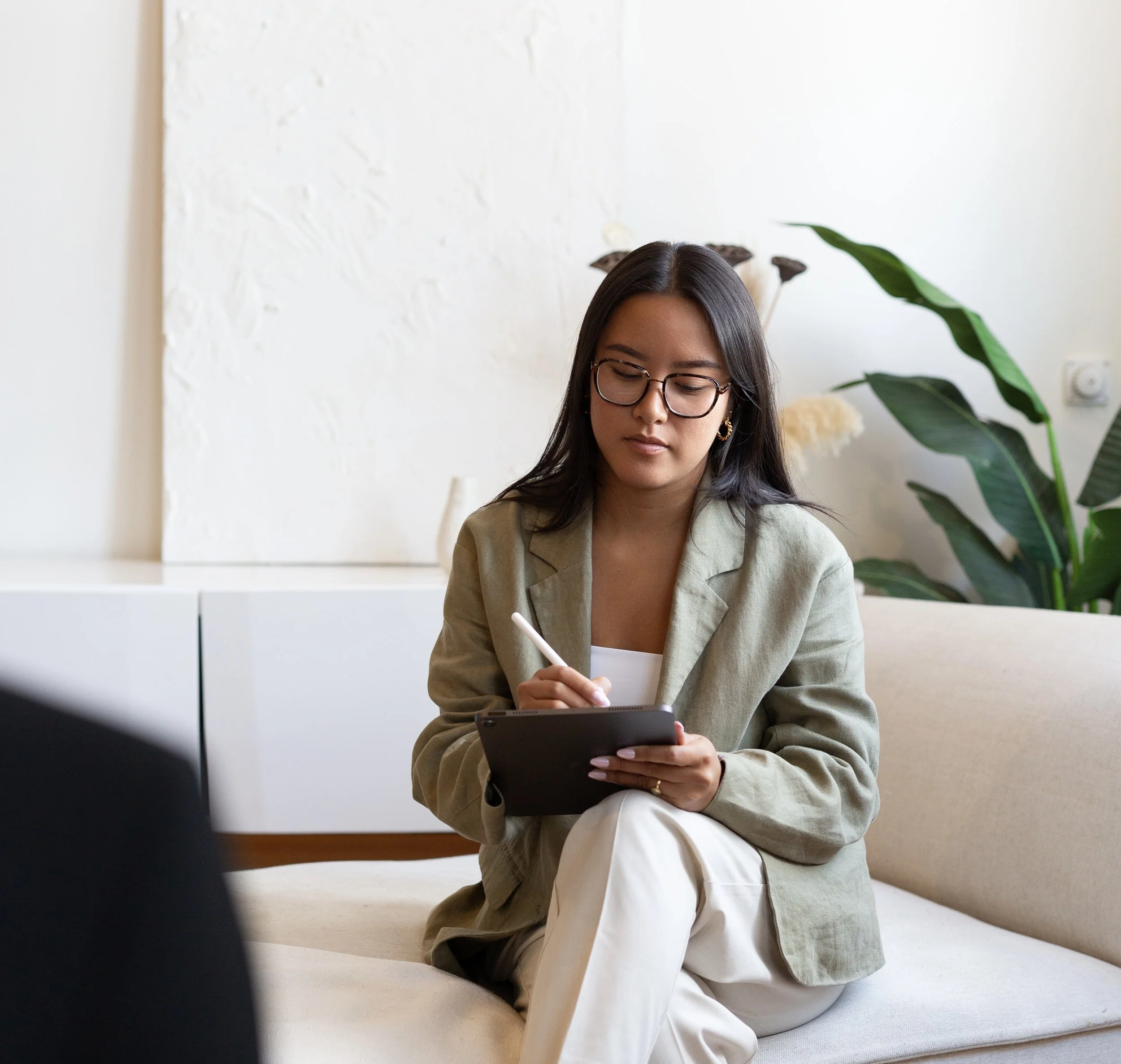Therapist taking notes during a psychotherapy session in a bright, neutral office setting.