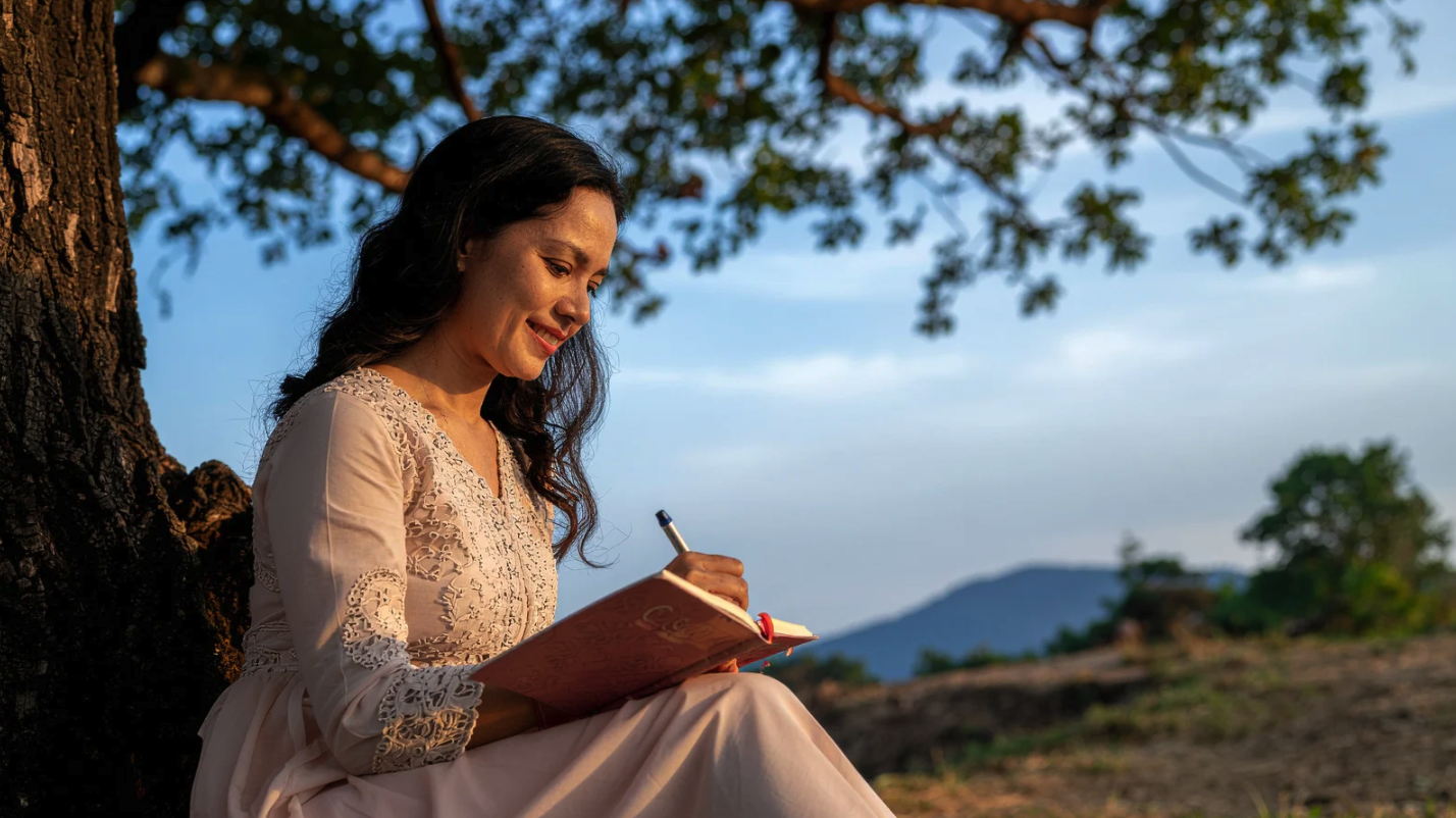 person writing in a journal outdoors, representing reflection before starting therapy