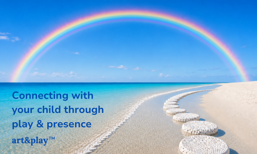 Rainbow over a sandy beach with footprints leading into the water and text that reads, 'Connecting with your child through play & presence art&playTM.'