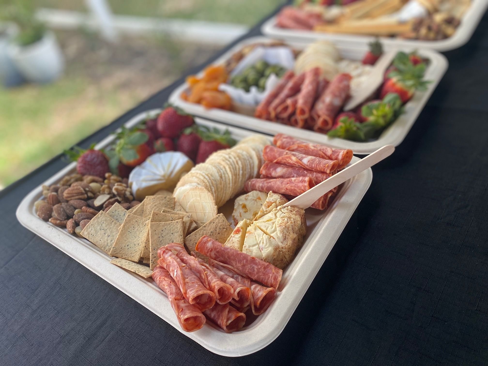 Charcuterie board with assorted meats, cheeses, crackers, nuts, strawberries, and dried fruits on a table.