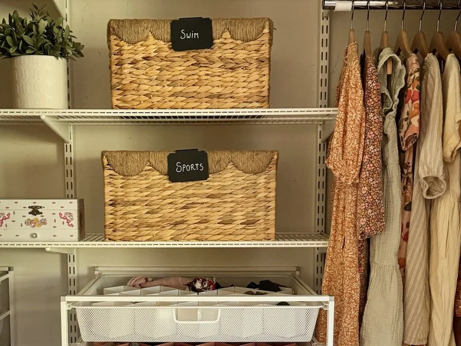 Closet organized with hanging clothes, labeled wicker baskets for 'Swim' and 'Sports'. San Anselmo, CA.