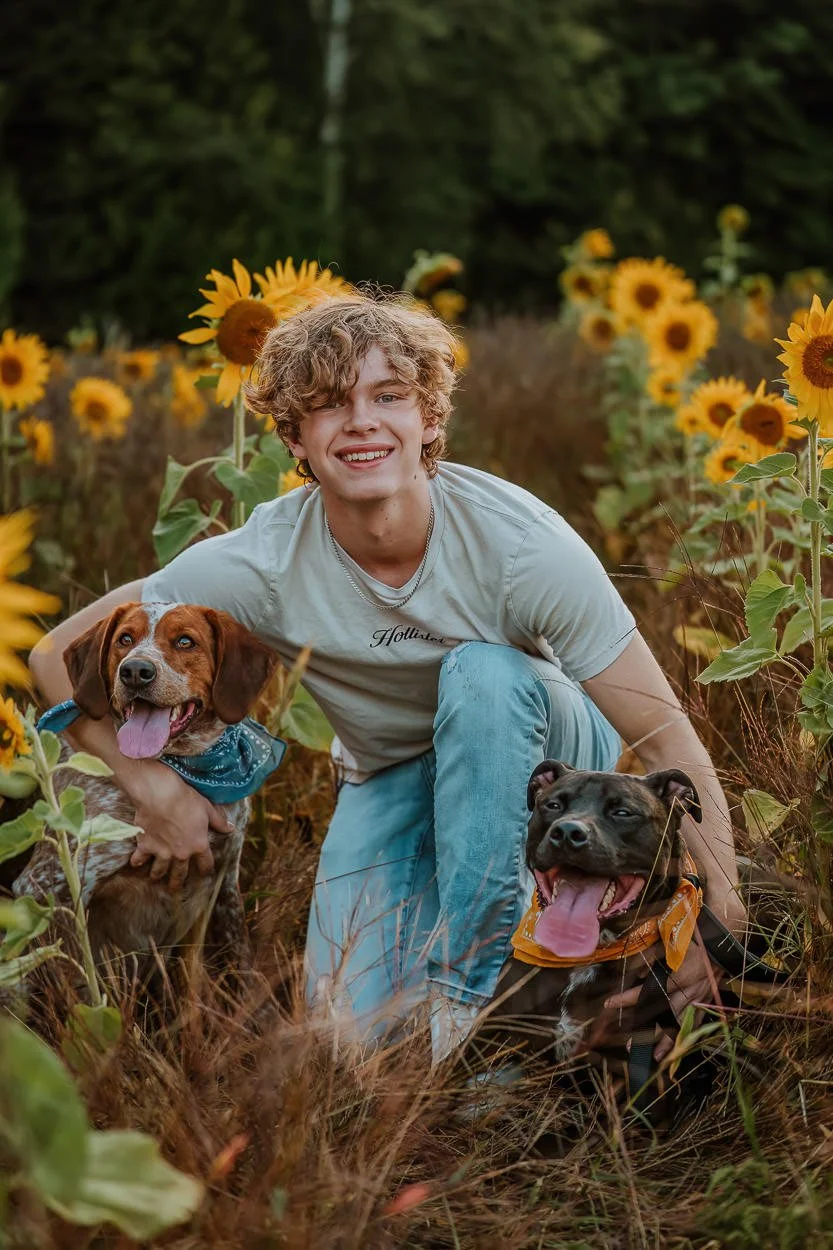 high school senior portraits with two dogs in a northern michigan sunflower field