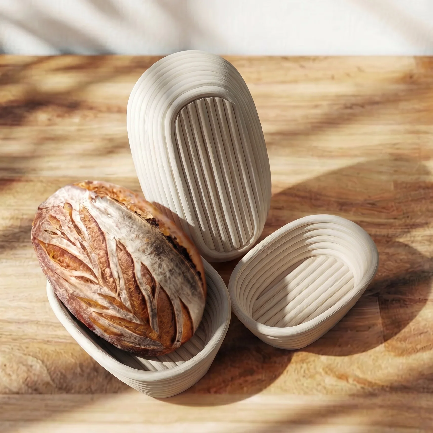 Handwoven oval rattan proofing baskets with baked sourdough loaf