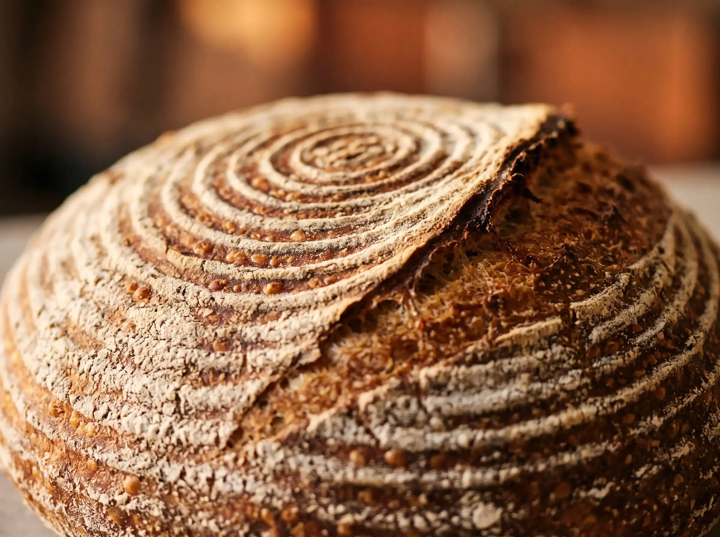 Close-up of a liner-proofed sourdough loaf with a smoother crust and decorative scoring