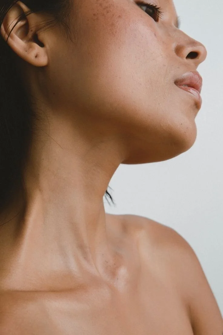 Close-up of a woman's face and neck, showing her smooth skin and natural features.
