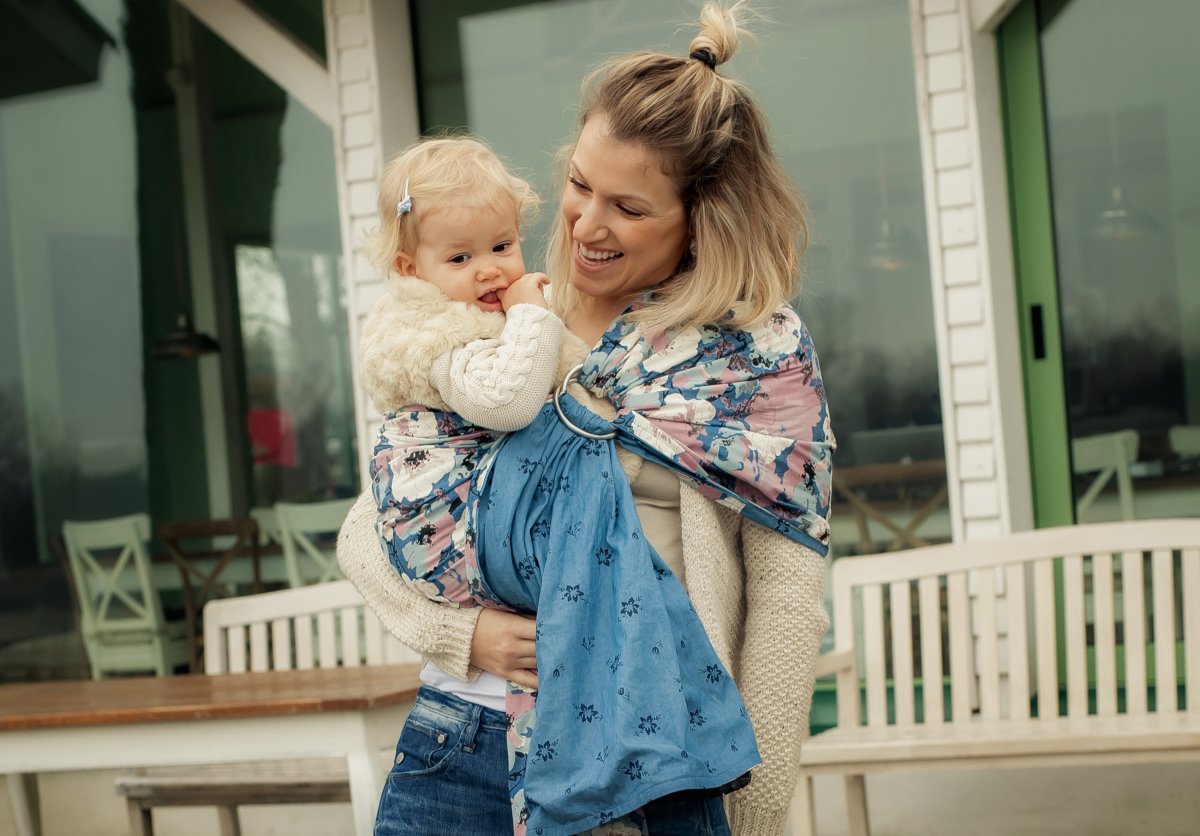 A nebraska mom is joyfully wearing her baby in a ring sling.